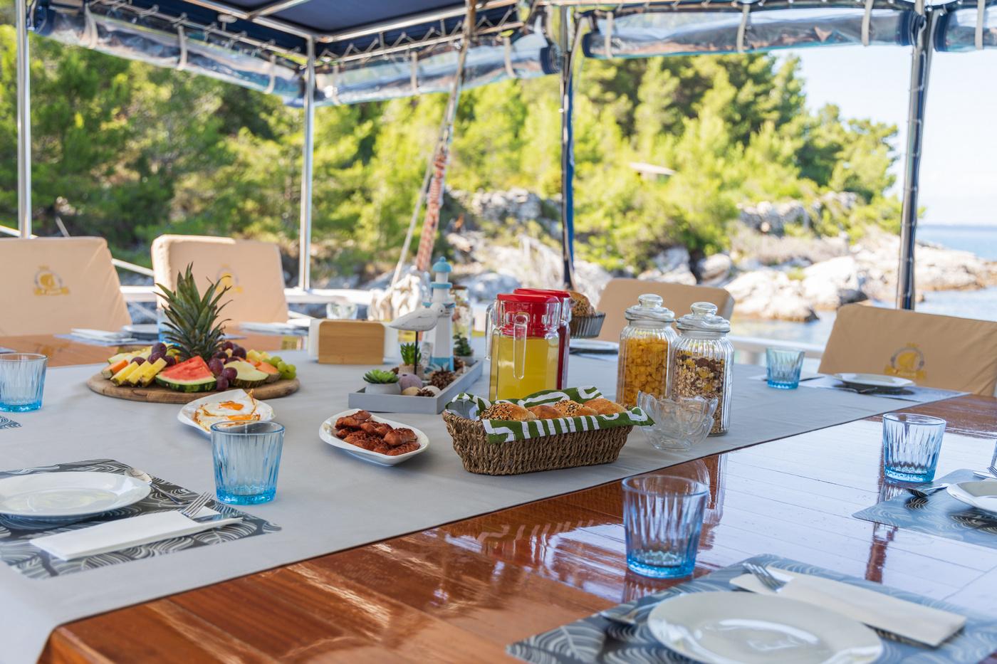 yacht breakfast table with fresh fruit platter, juice dispenser, cereals and blue glassware