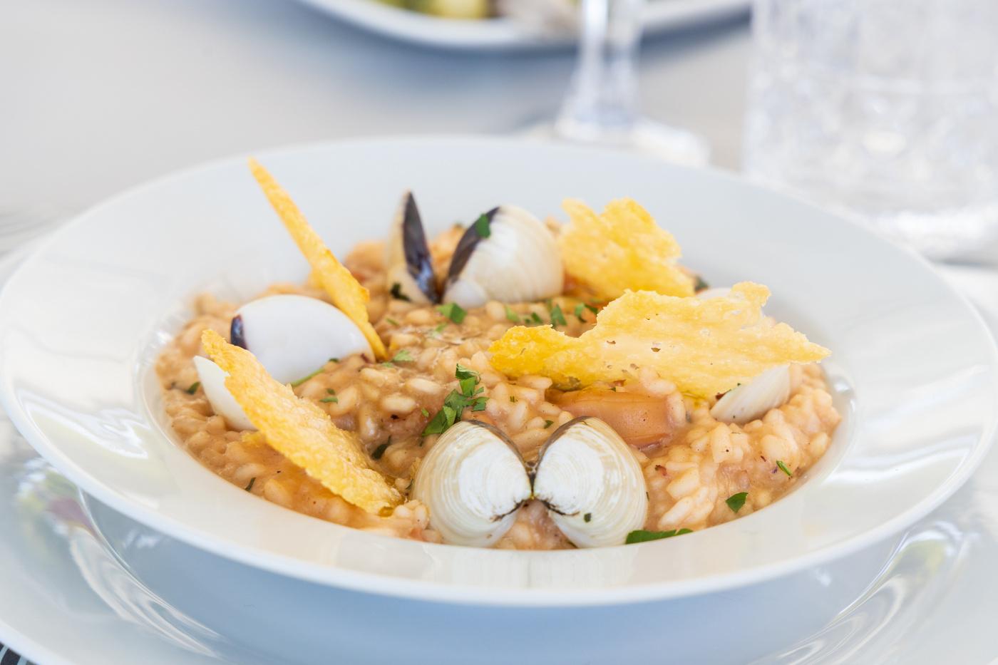 gourmet seafood risotto served in white bowl with clams and crispy garnish