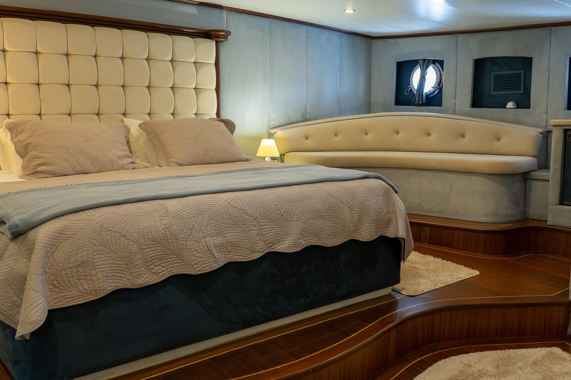 yacht cabin interior with quilted headboard bed and curved cream upholstered seating
