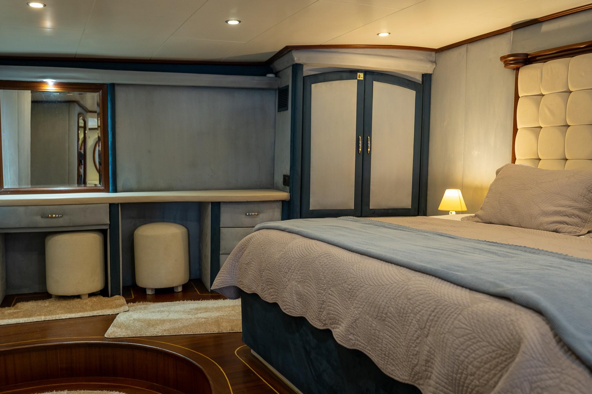 yacht cabin interior with double bed, built-in vanity desk, mirror and wardrobe storage
