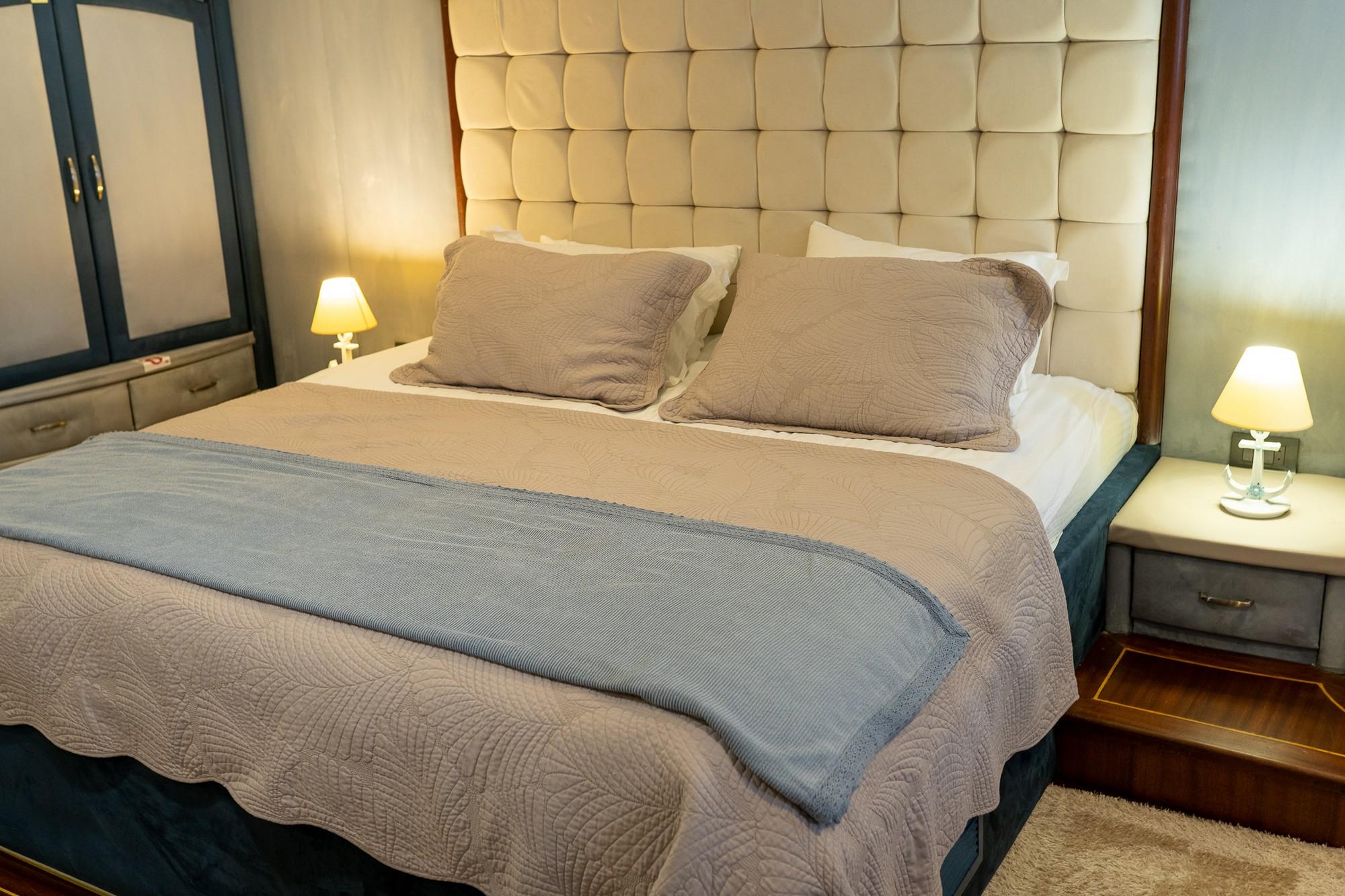 yacht cabin interior with beige tufted leather headboard, double bed, and bedside tables