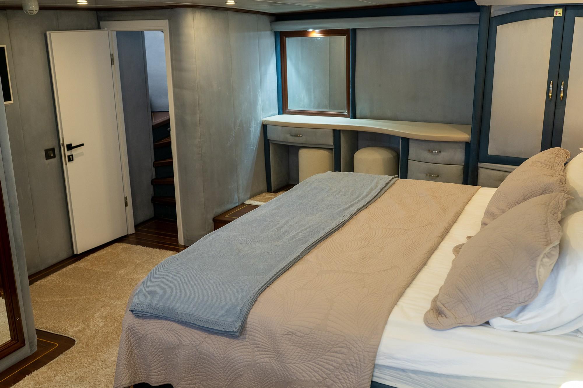 yacht guest cabin featuring double bed with blue runner, built-in desk vanity area and wardrobes