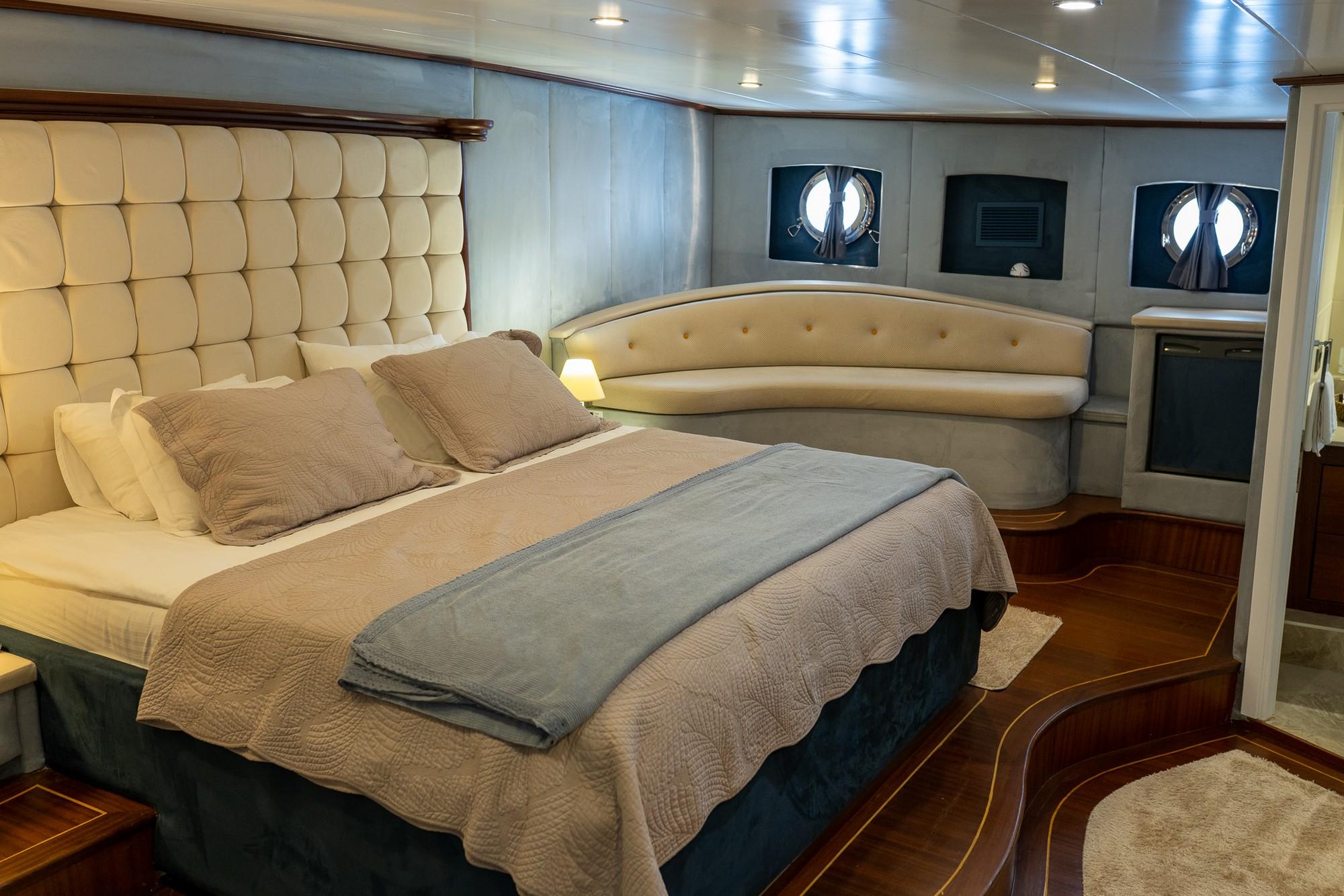 luxury yacht master cabin featuring king bed with tufted headboard and two portholes