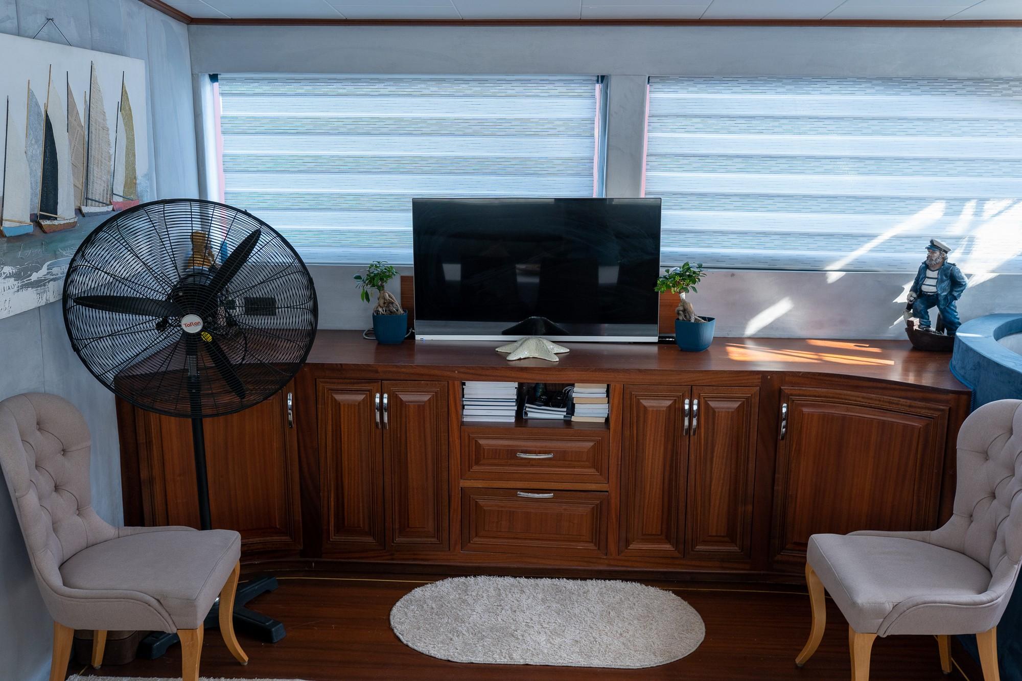 yacht entertainment lounge with large flat screen TV on wooden cabinet and gray armchairs