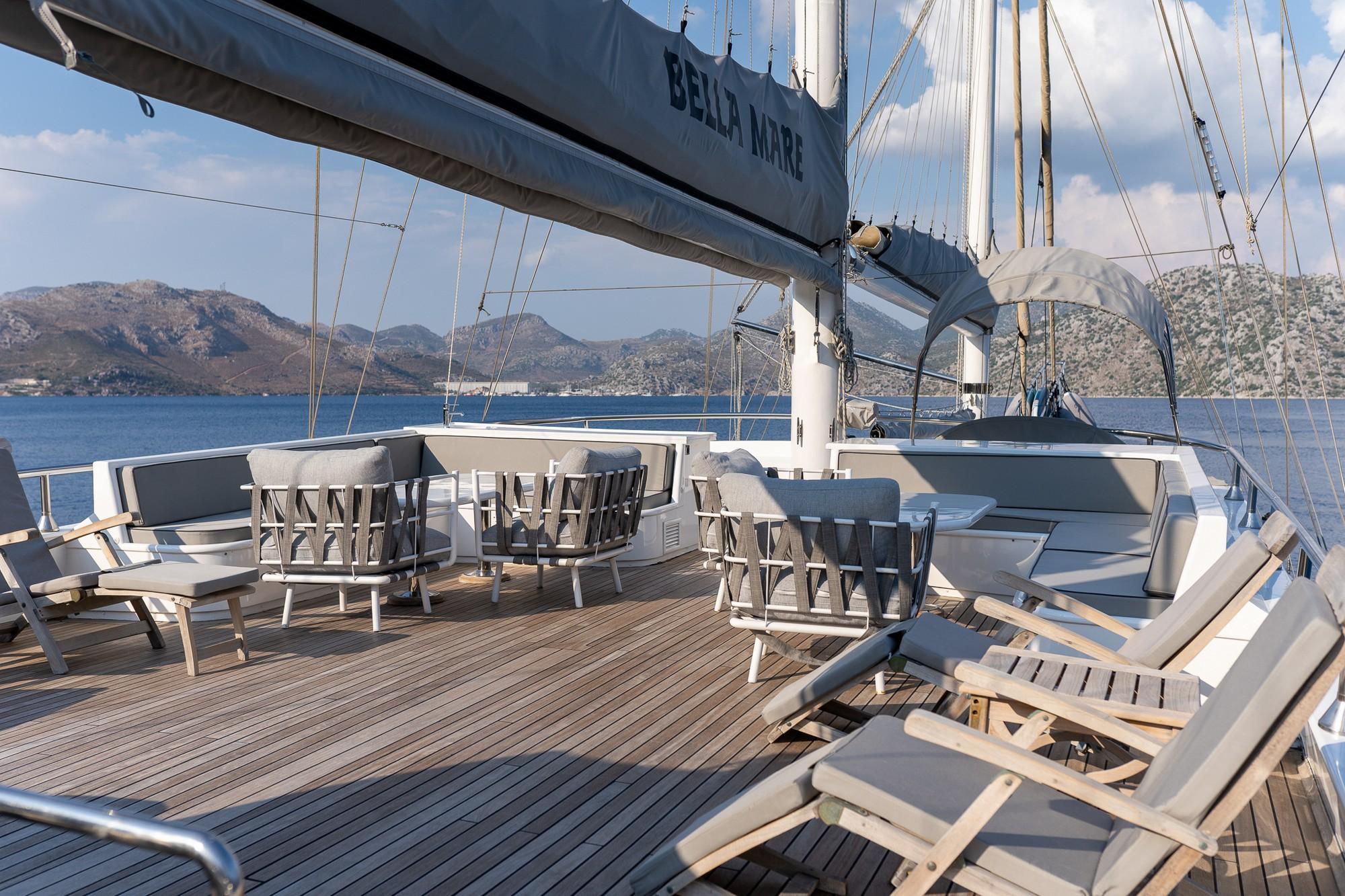 main deck dining area with white table, chairs and cushioned seating on teak decking