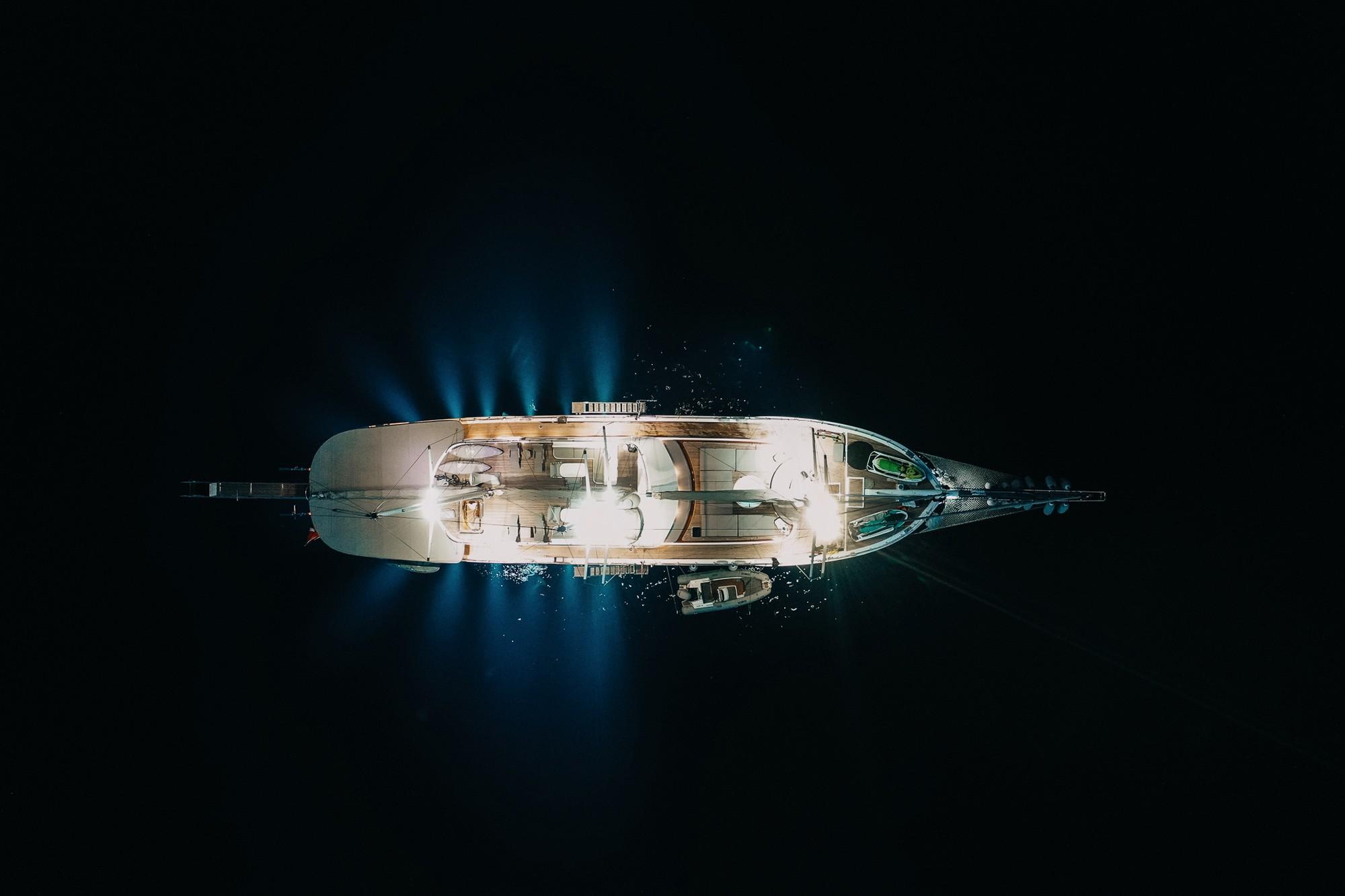 aerial night shot of luxury yacht with underwater lighting and tender boat