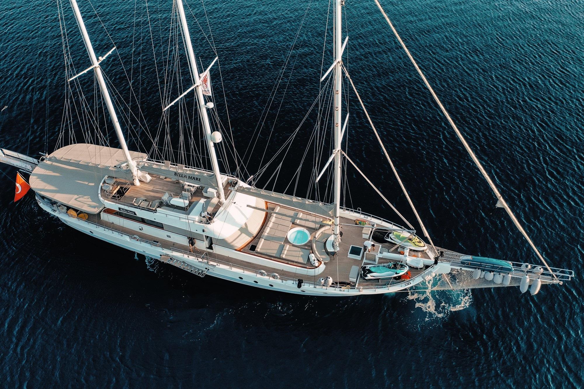 Aerial view of white luxury gulet yacht with three masts anchored in deep blue water