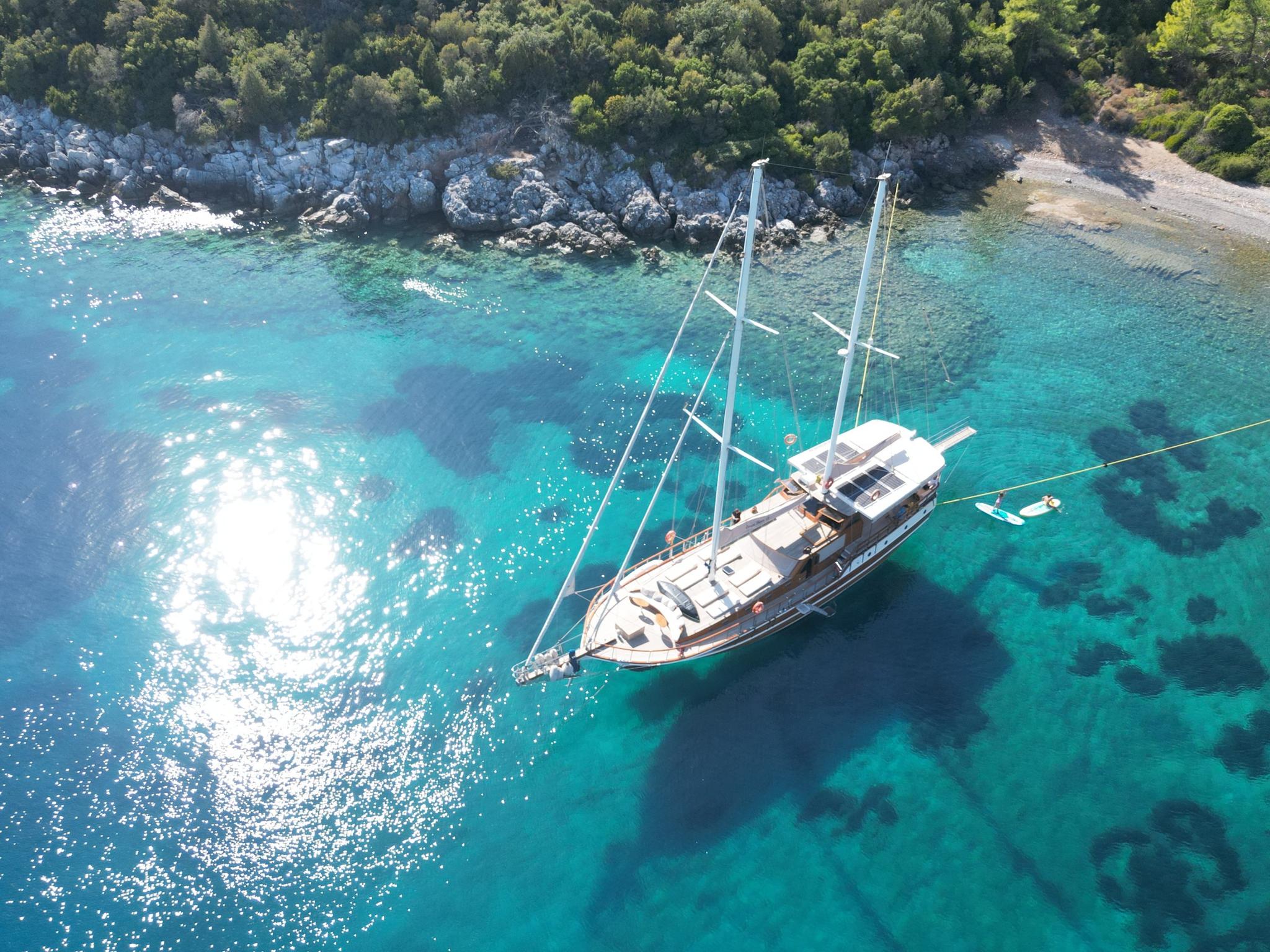 aerial view of white gulet yacht anchored in crystal clear turquoise Mediterranean bay