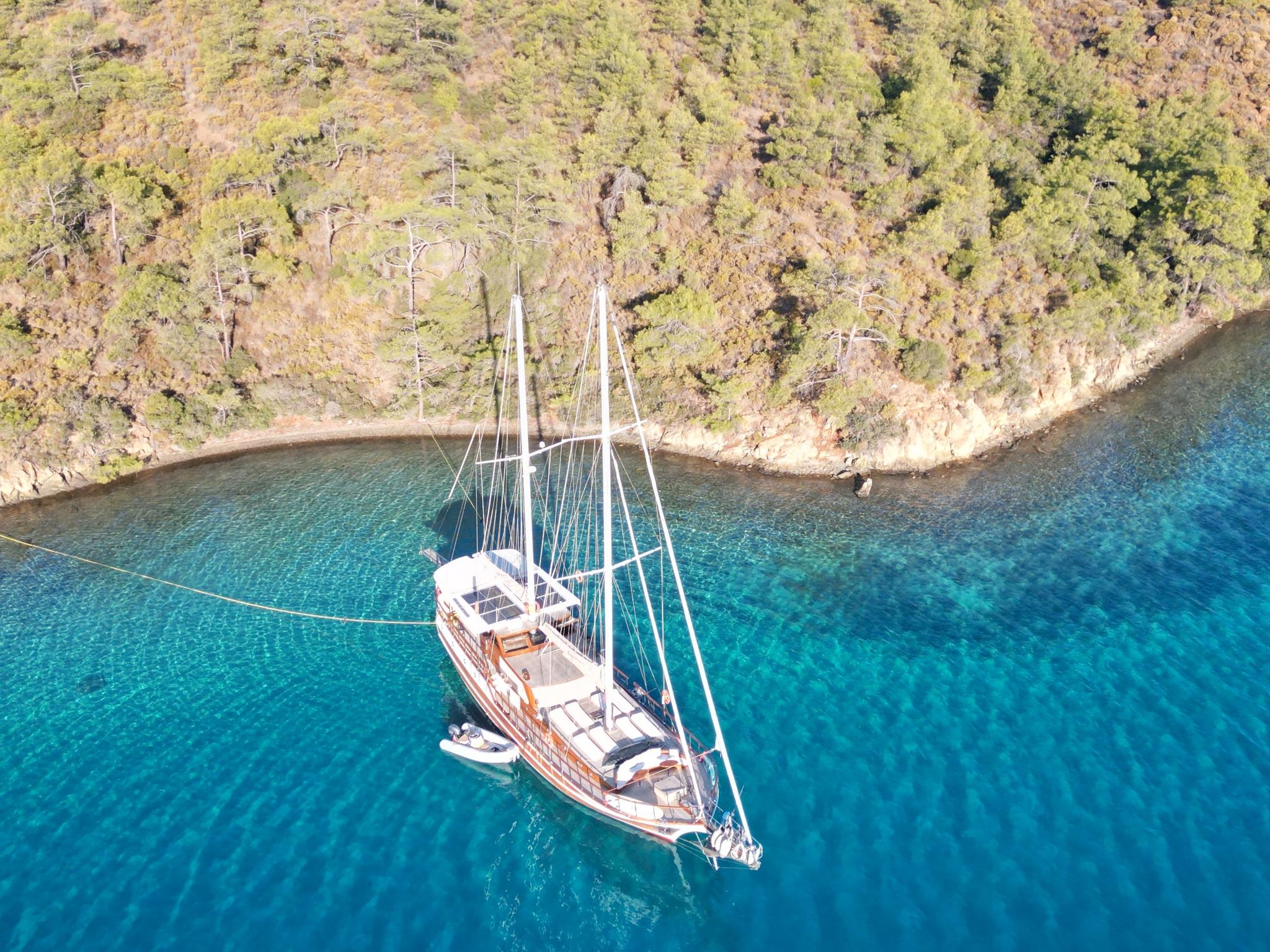 aerial view of traditional wooden gulet yacht anchored in crystal clear turquoise Mediterranean bay