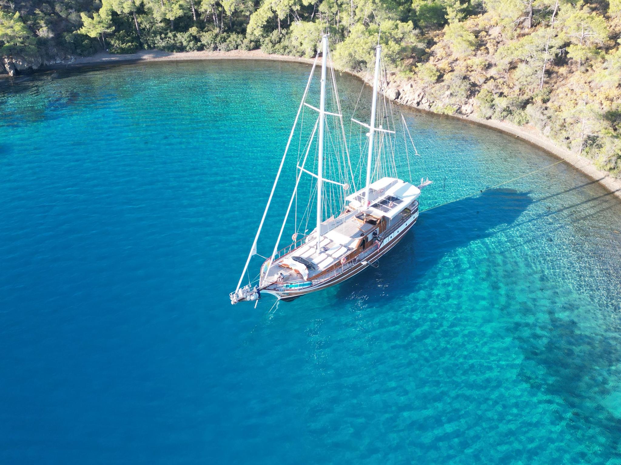 aerial view of traditional gulet yacht anchored in crystal clear turquoise Mediterranean bay