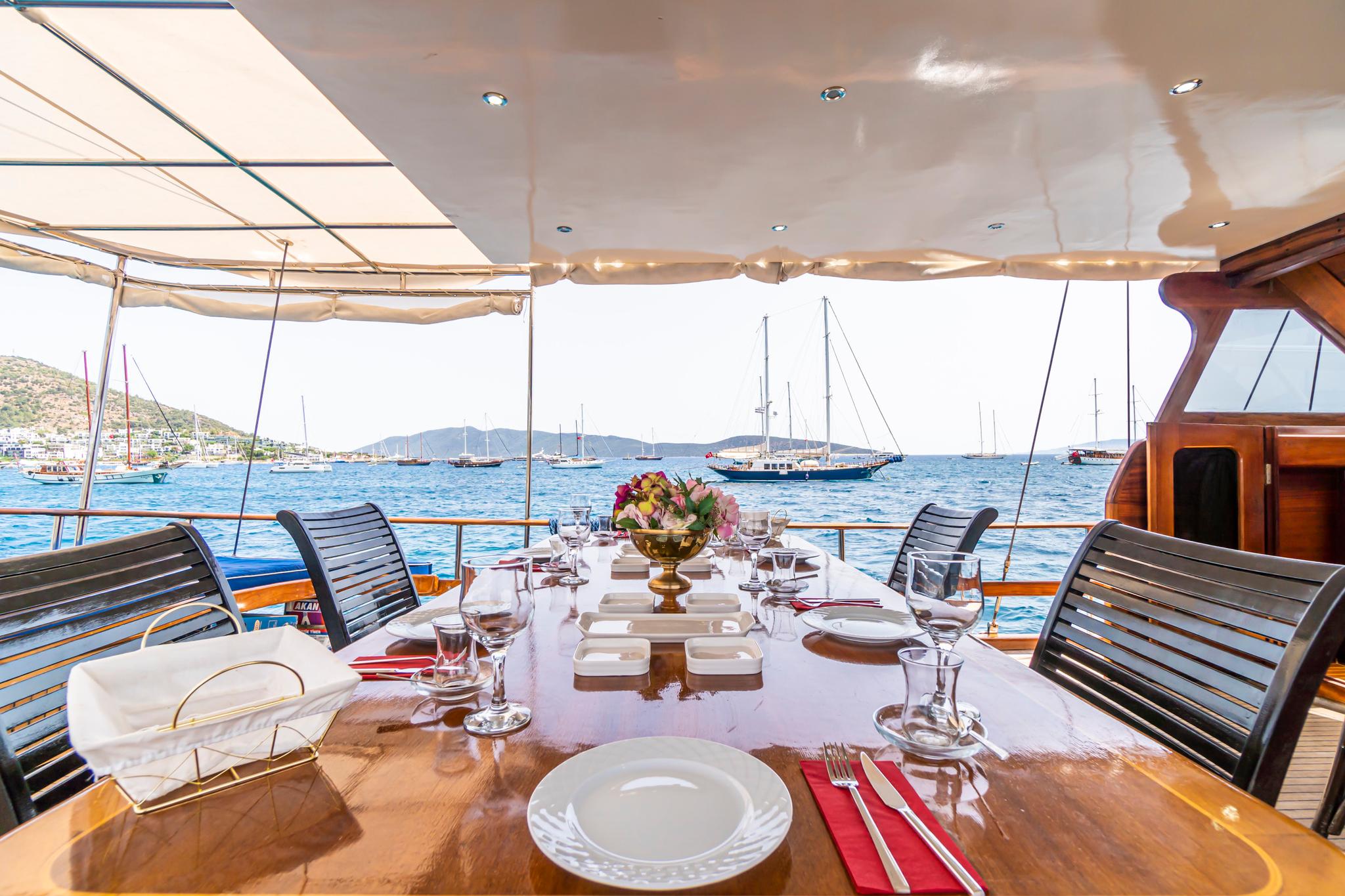 aft deck dining area with formal table setting overlooking Mediterranean harbor with yachts