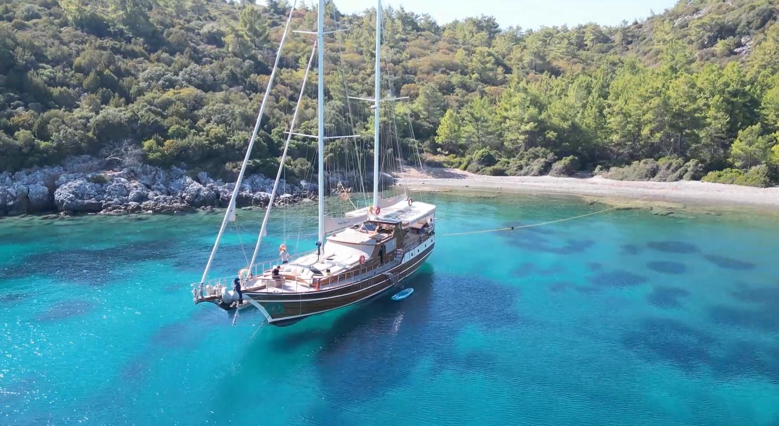 aerial view of traditional wooden gulet yacht anchored in crystal clear turquoise Mediterranean bay