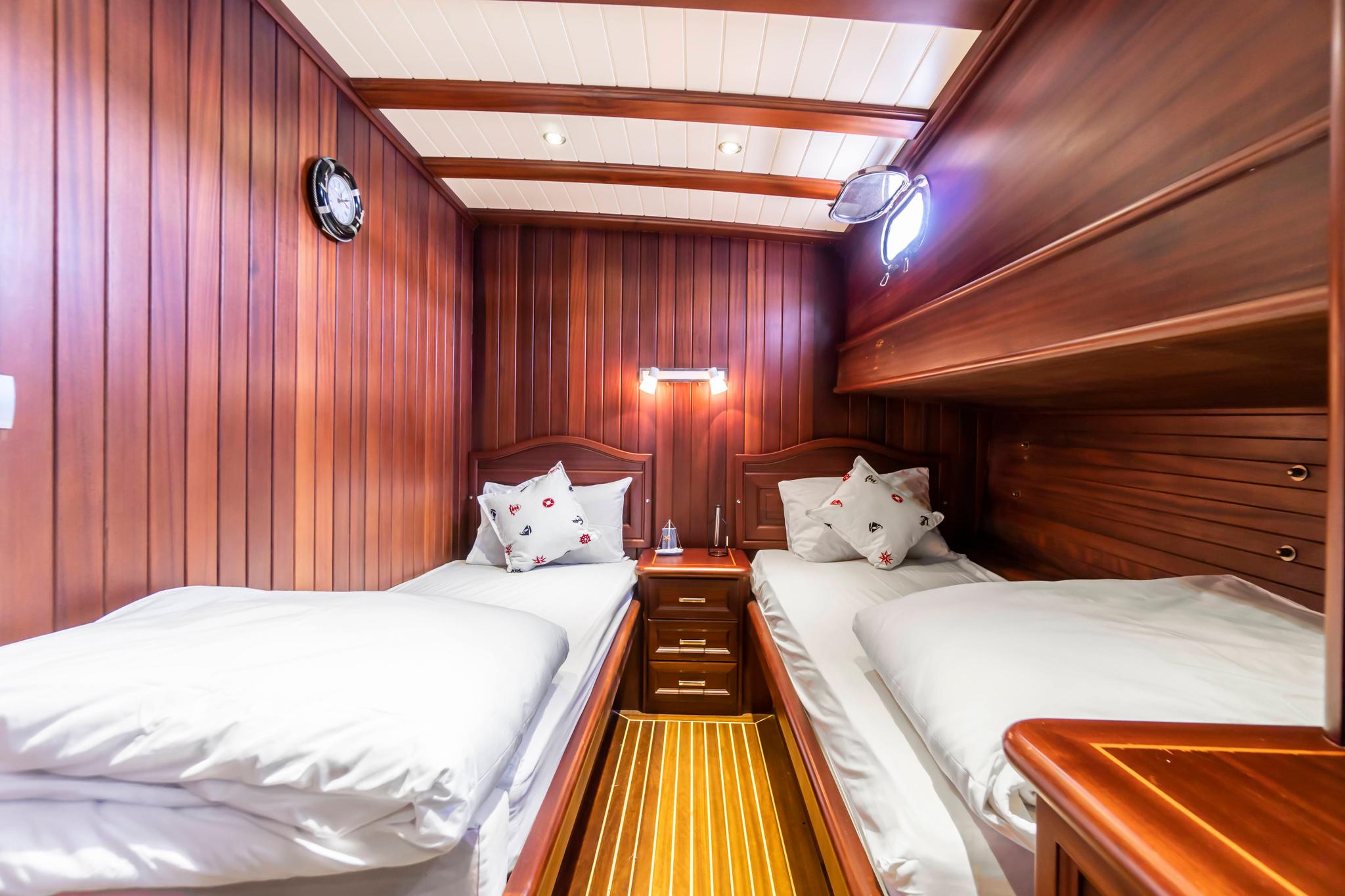 yacht twin guest cabin with rich wood paneling and two single beds