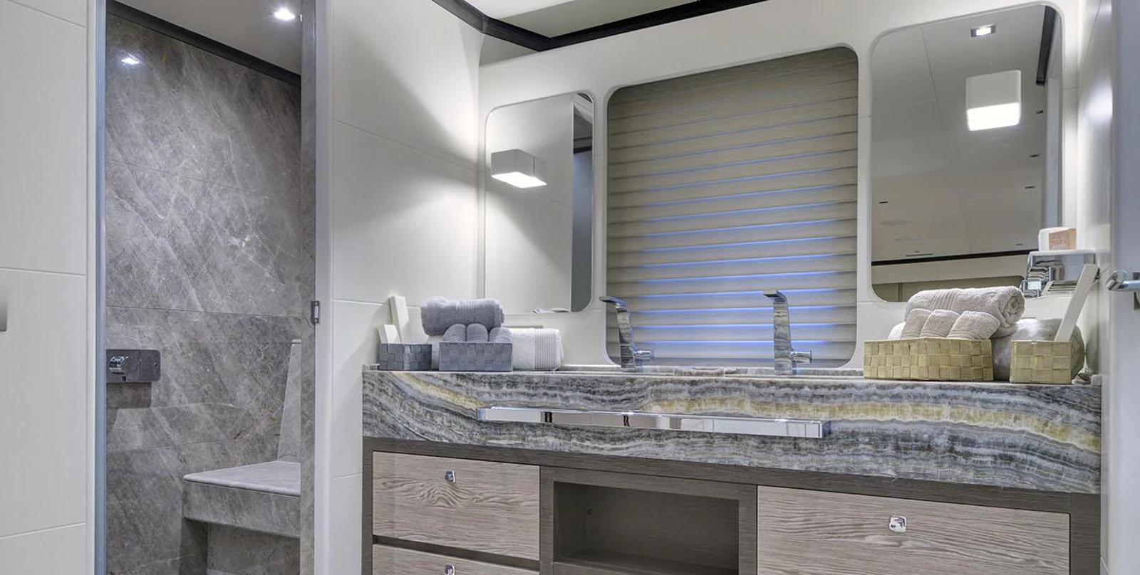 luxury yacht bathroom featuring marble countertop vanity with dual sinks and illuminated mirror