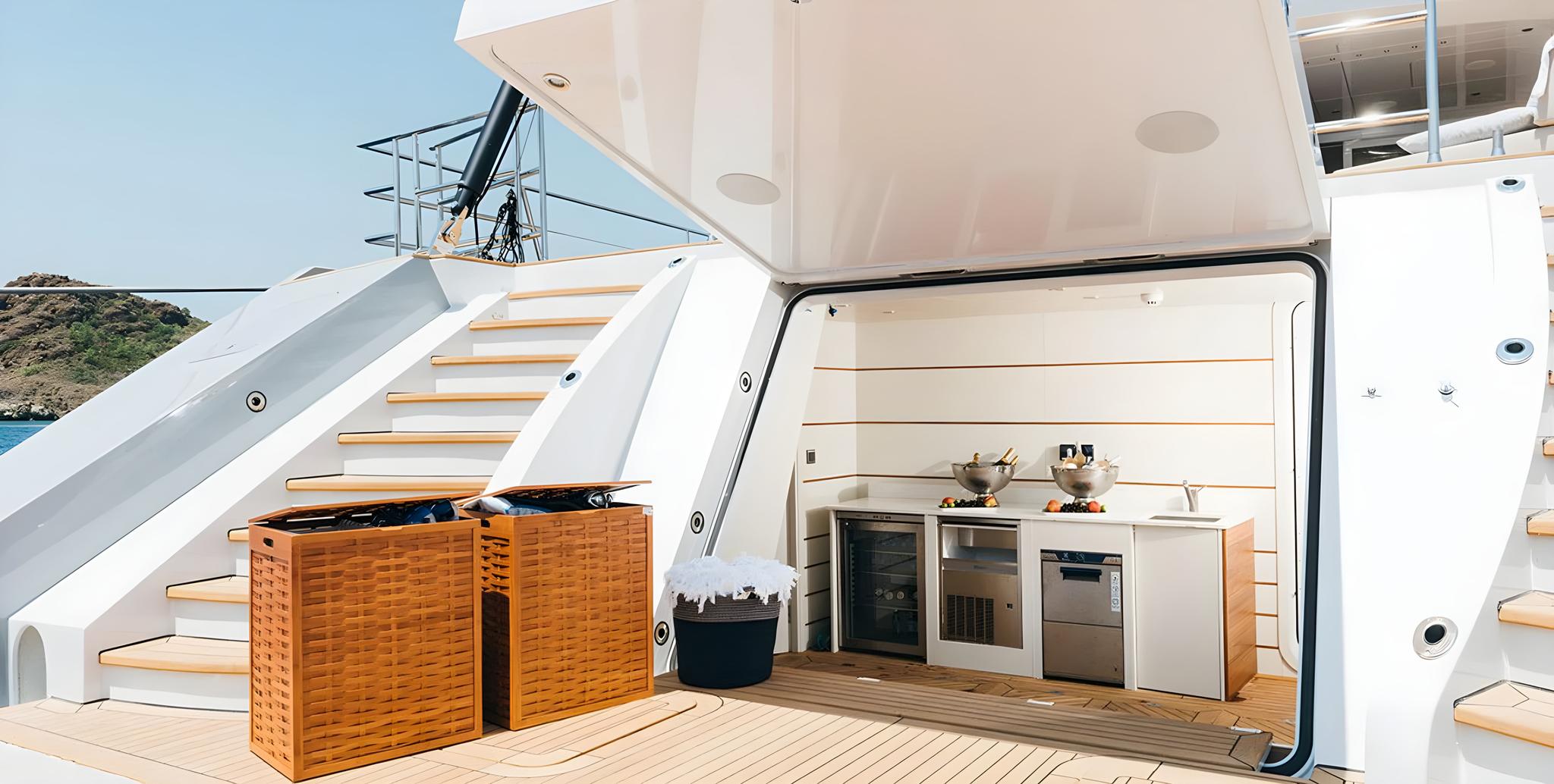 yacht aft deck galley kitchen with stainless steel appliances and wicker storage baskets