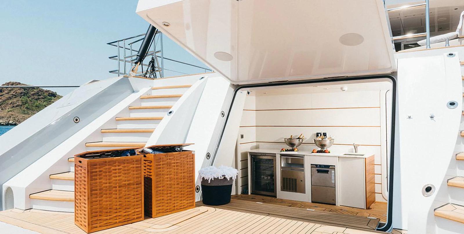 yacht aft deck galley kitchen with stainless steel appliances and wicker storage baskets