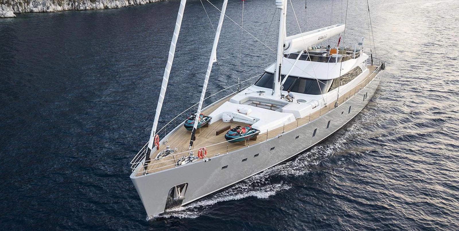 aerial view of white sailing yacht underway with two tenders on foredeck