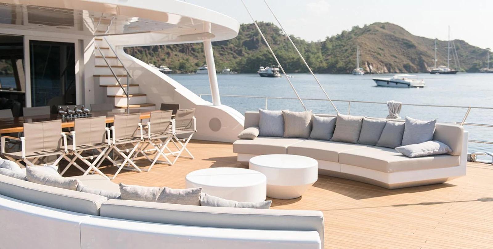 yacht main deck with curved sectional sofa, white coffee tables and teak flooring