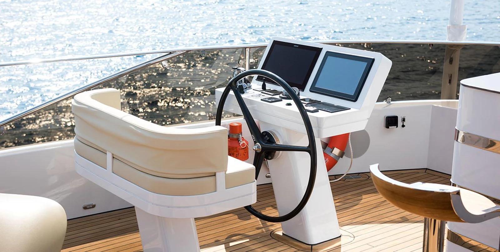 yacht flybridge helm station with black steering wheel, dual navigation screens, and curved seating