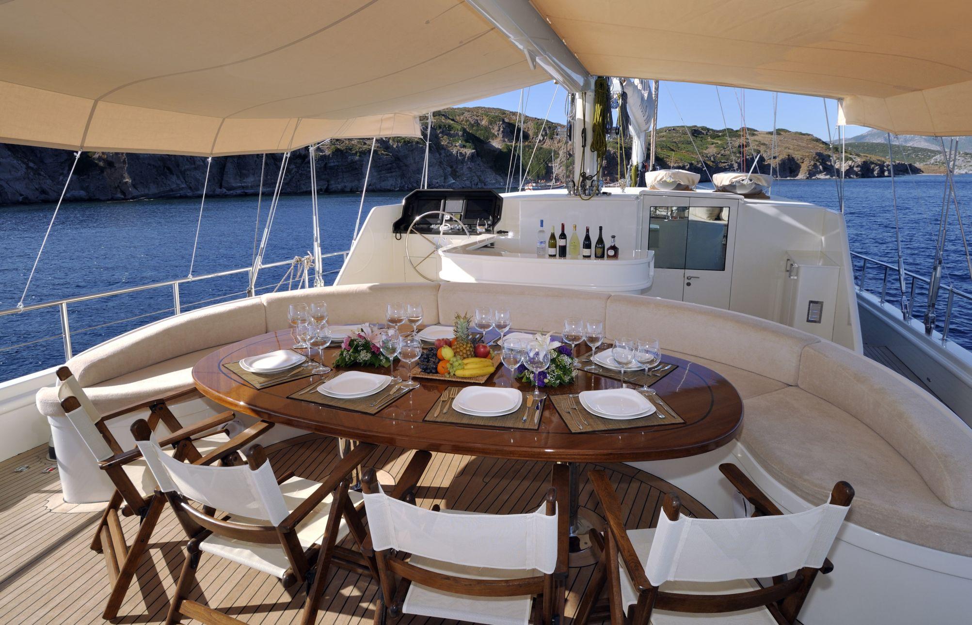 yacht aft deck dining area with set table, wine glasses, plates and fruit centerpiece