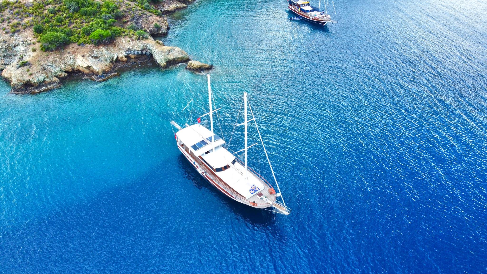 aerial view of wooden gulet yacht anchored in crystal clear turquoise Mediterranean bay