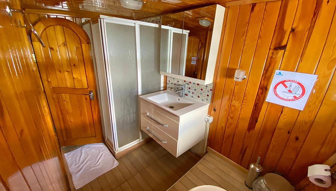 yacht bathroom featuring white vanity unit with basin, mosaic tile backsplash, and shower enclosure