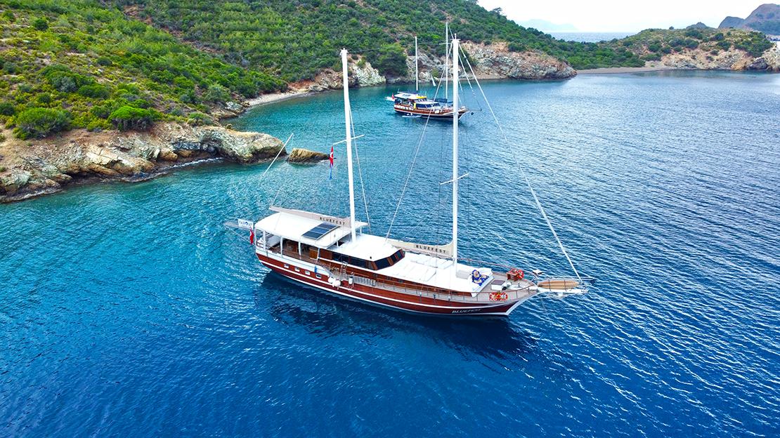 aerial view of traditional wooden gulet yacht anchored in crystal clear turquoise Mediterranean bay