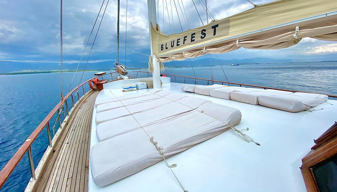 Bow deck of luxury gulet with white cushioned sun loungers and rigging