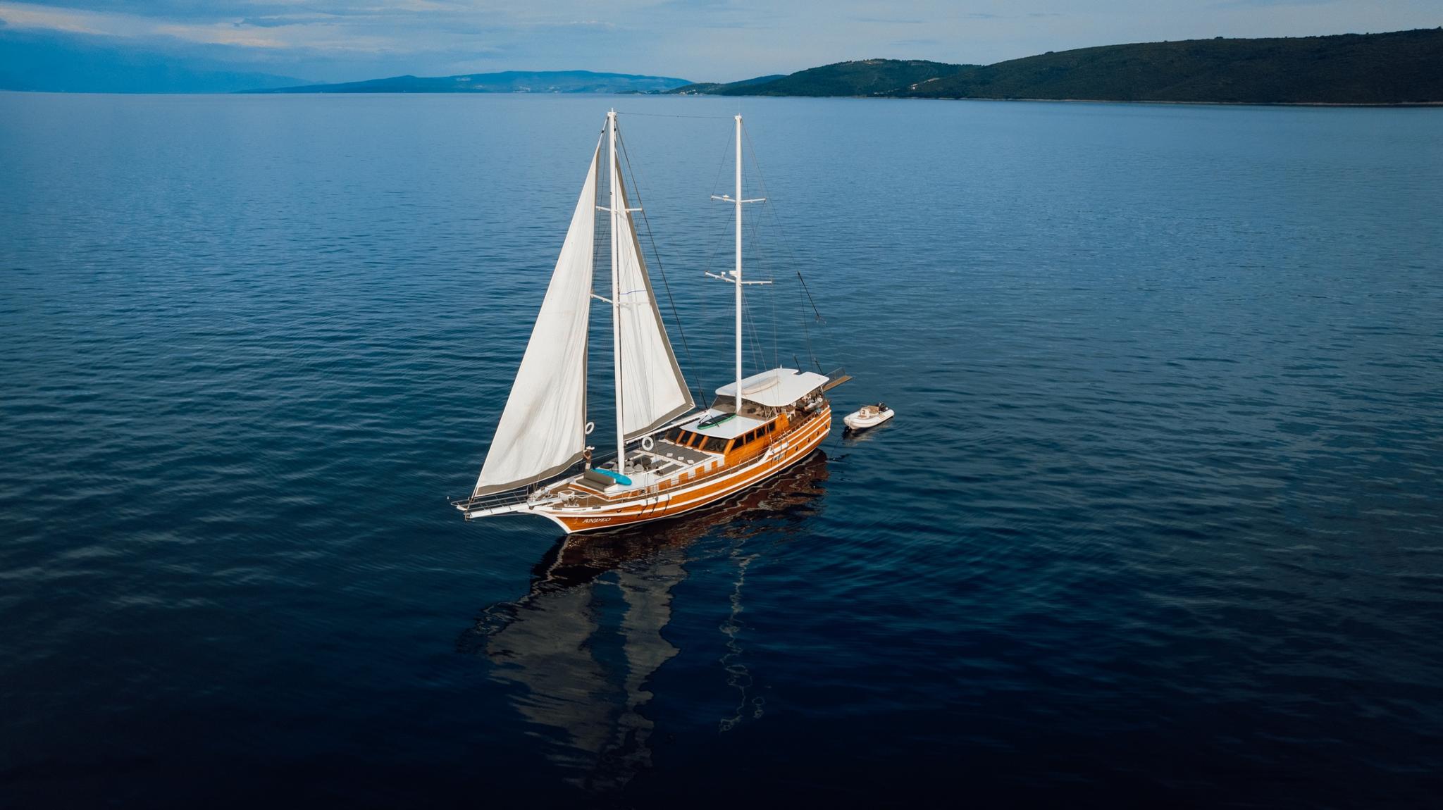 aerial view of traditional wooden gulet under sail in calm blue waters