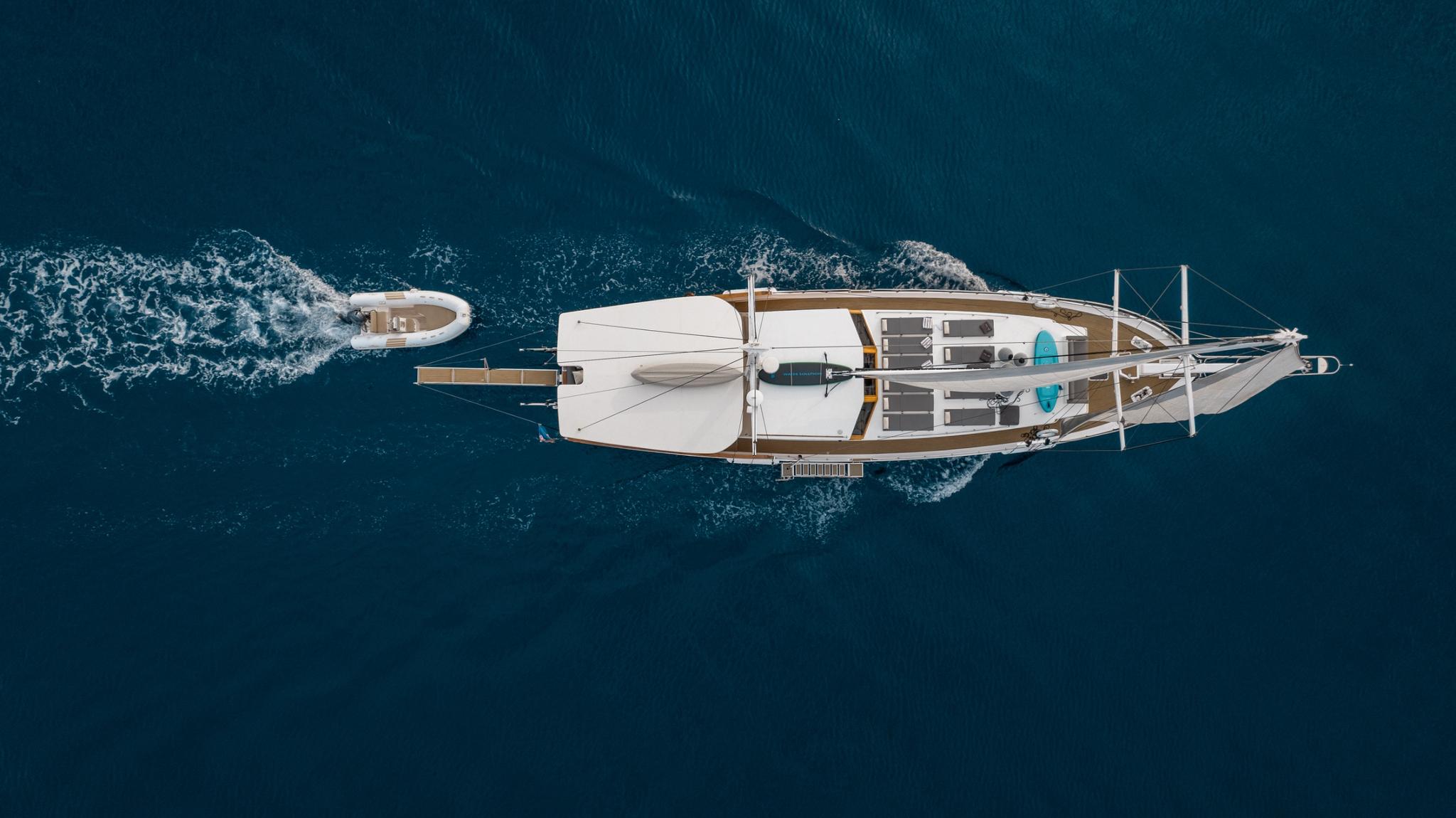 aerial drone view of white gulet yacht at anchor showing deck layout and swim platform