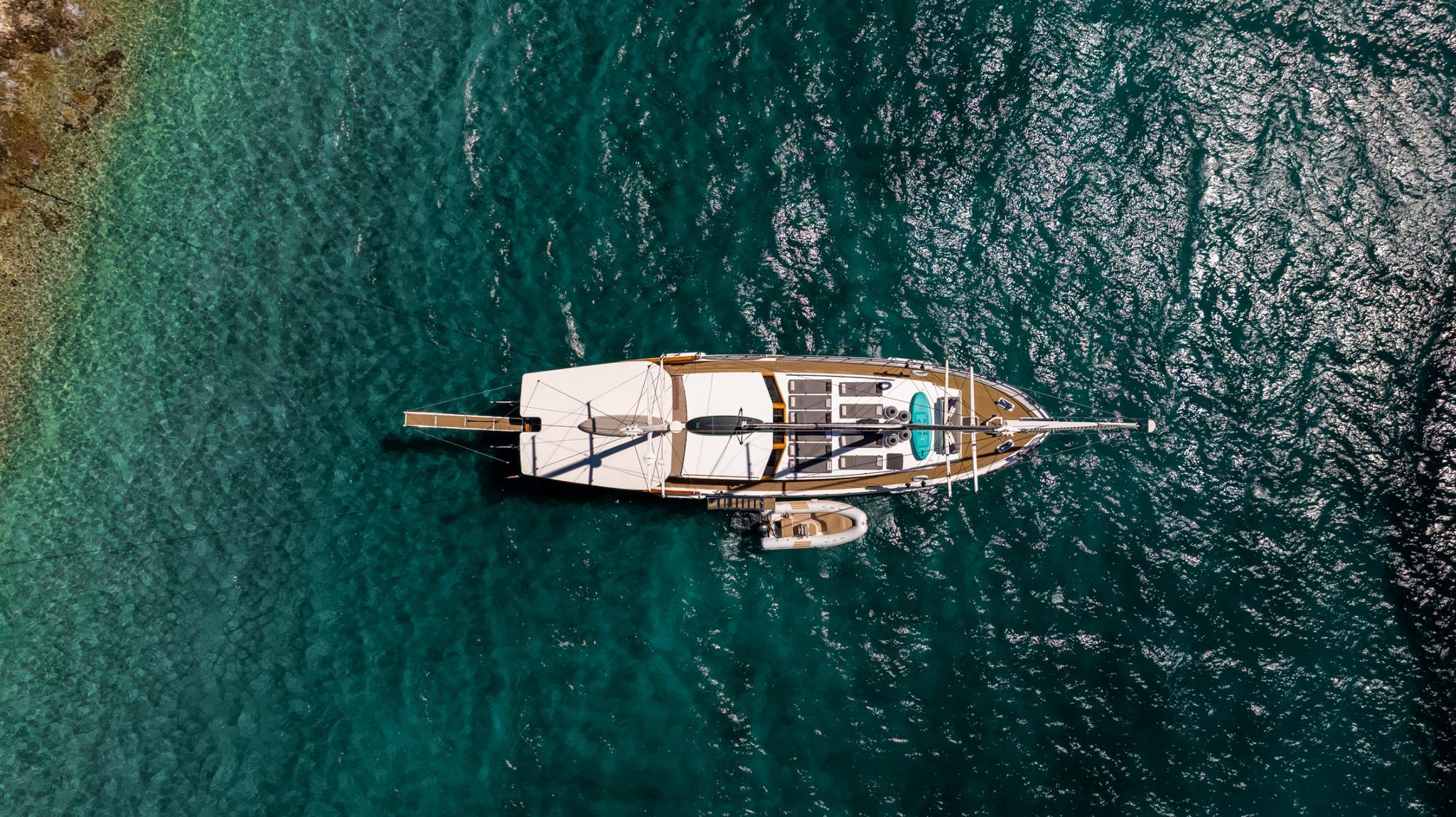 aerial view of traditional wooden gulet yacht anchored in crystal clear turquoise Mediterranean waters