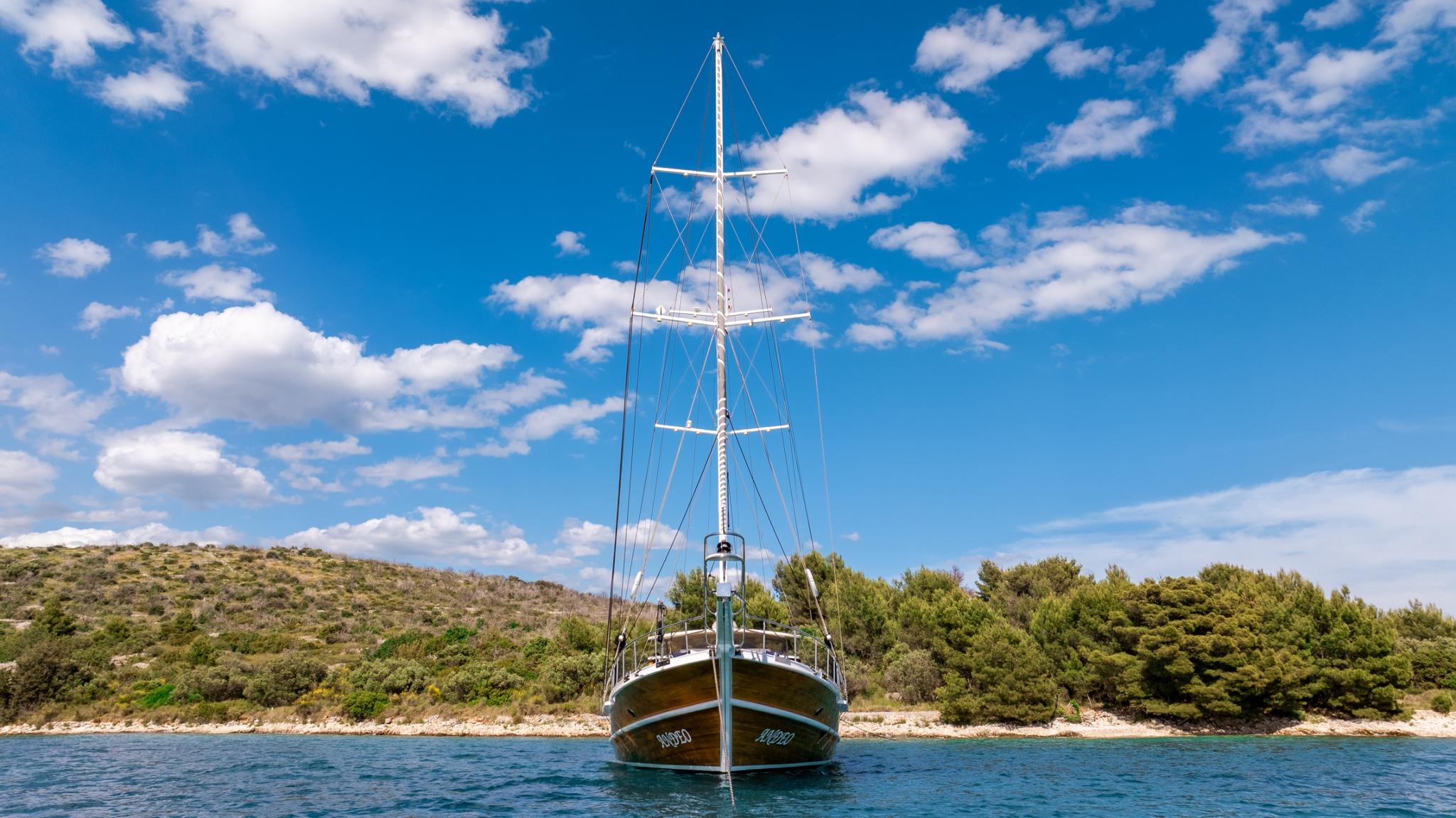 wooden gulet yacht anchored in turquoise bay with pine covered coastline