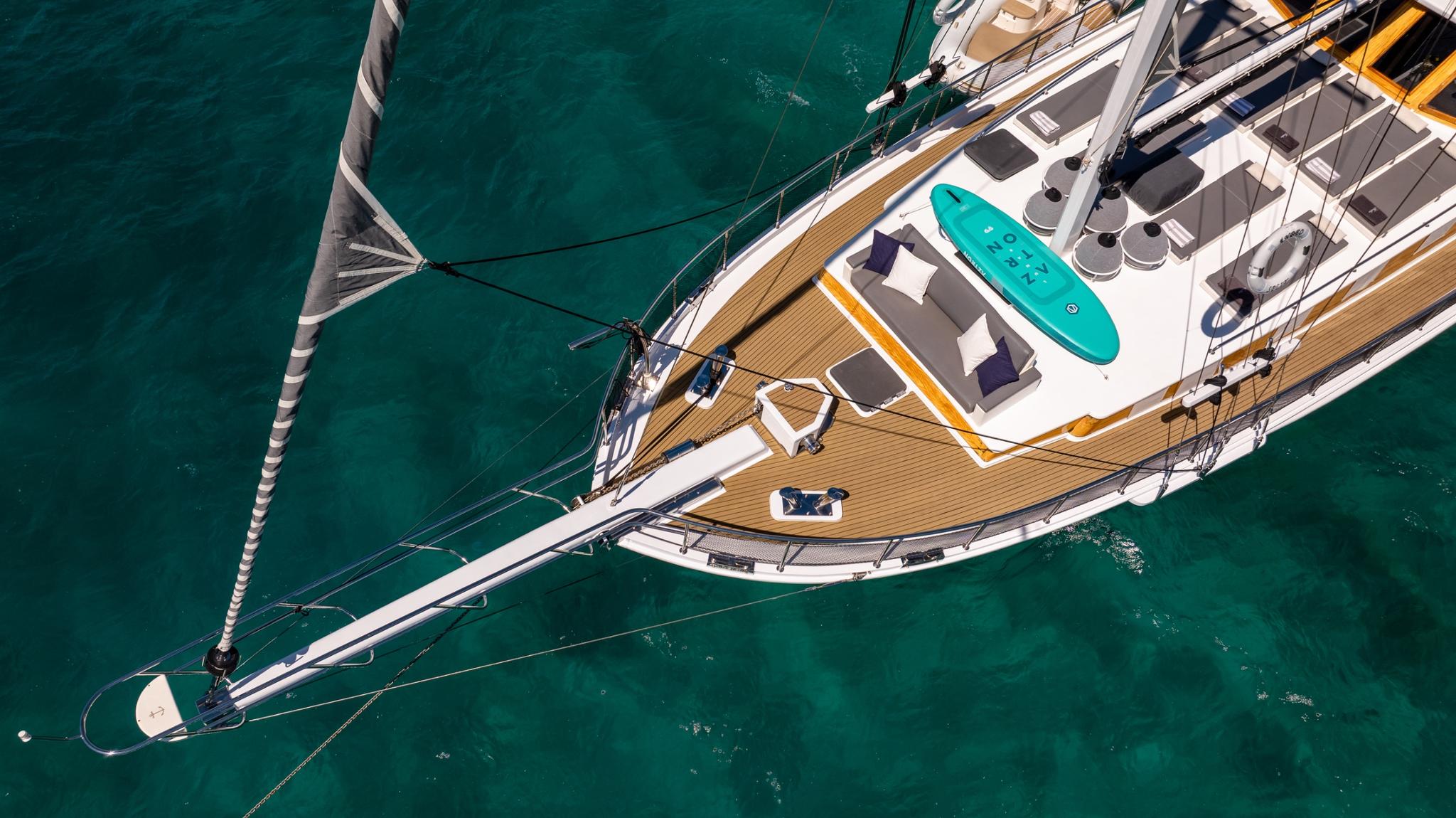 aerial view of white sailing yacht with teak decking and turquoise paddleboard on deck