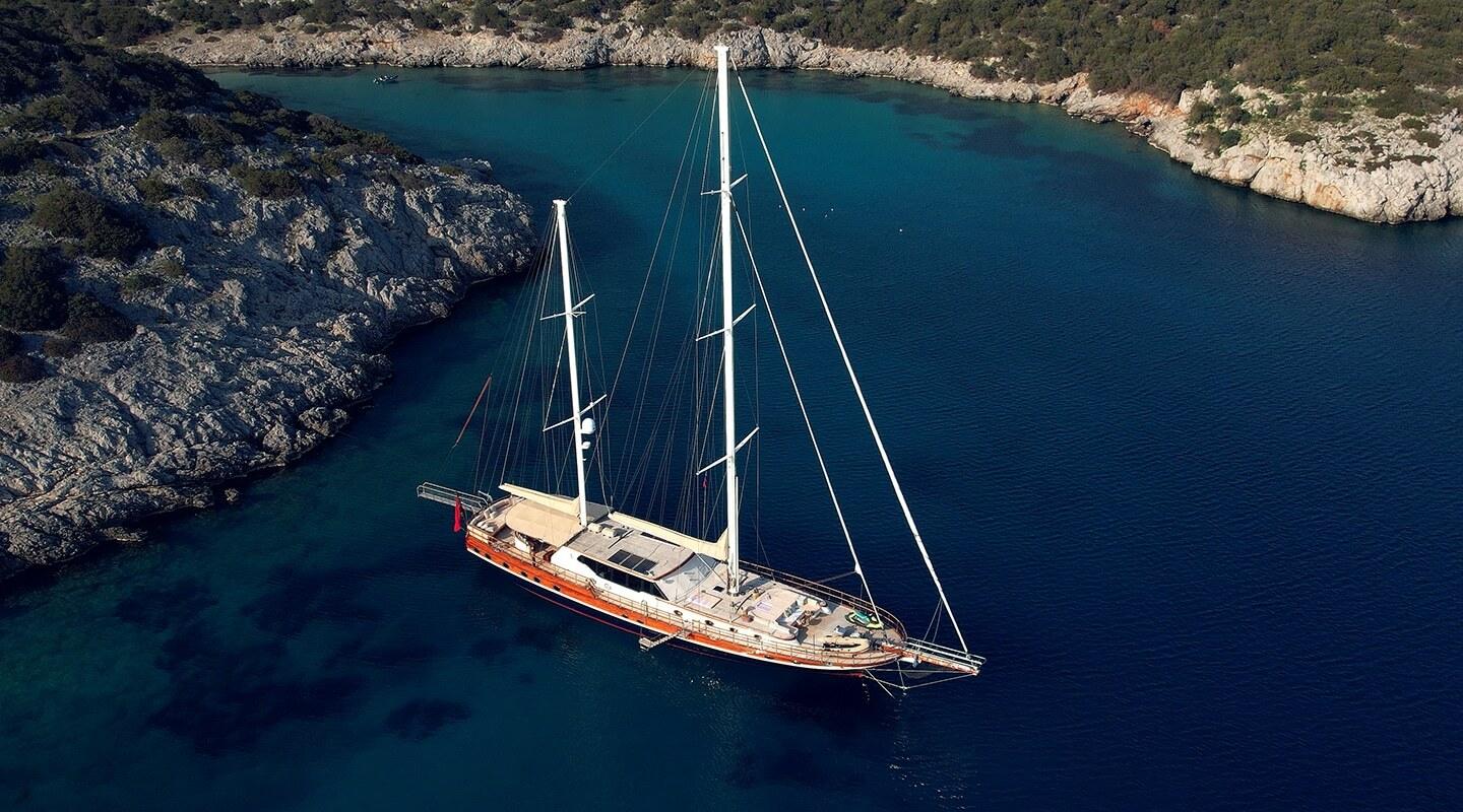 aerial view of traditional gulet yacht with two masts anchored in turquoise Mediterranean bay