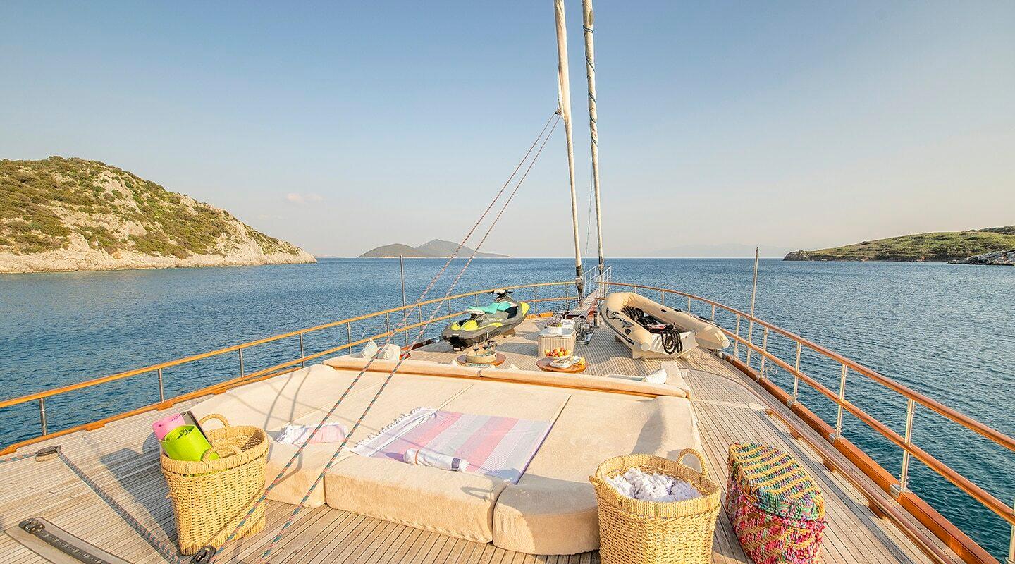 gulet bow deck with beige sun cushions, wicker storage baskets and stainless steel railings