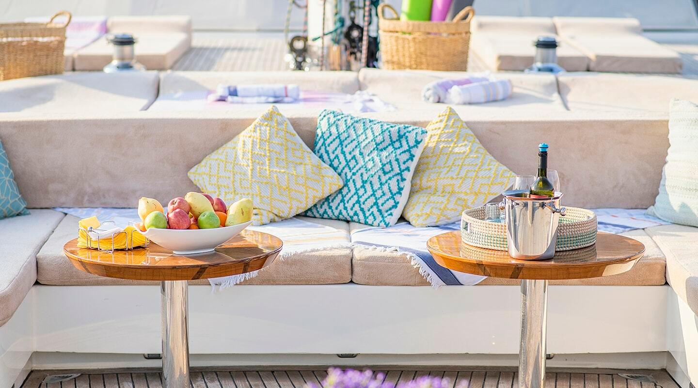 yacht salon lounge with beige seating, colorful geometric cushions and wooden side tables