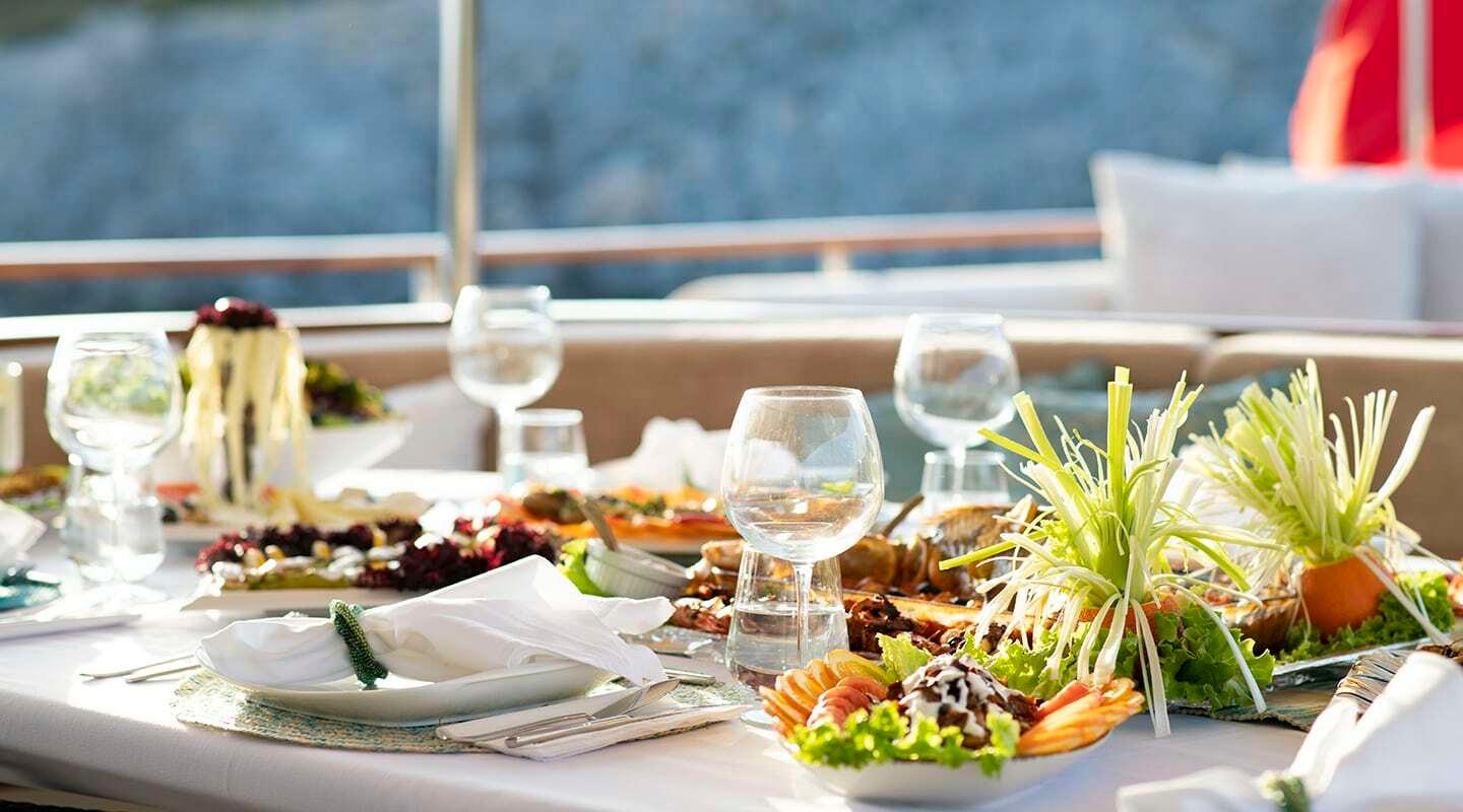elegant yacht dining table with fresh seafood platters, wine glasses and scenic water views