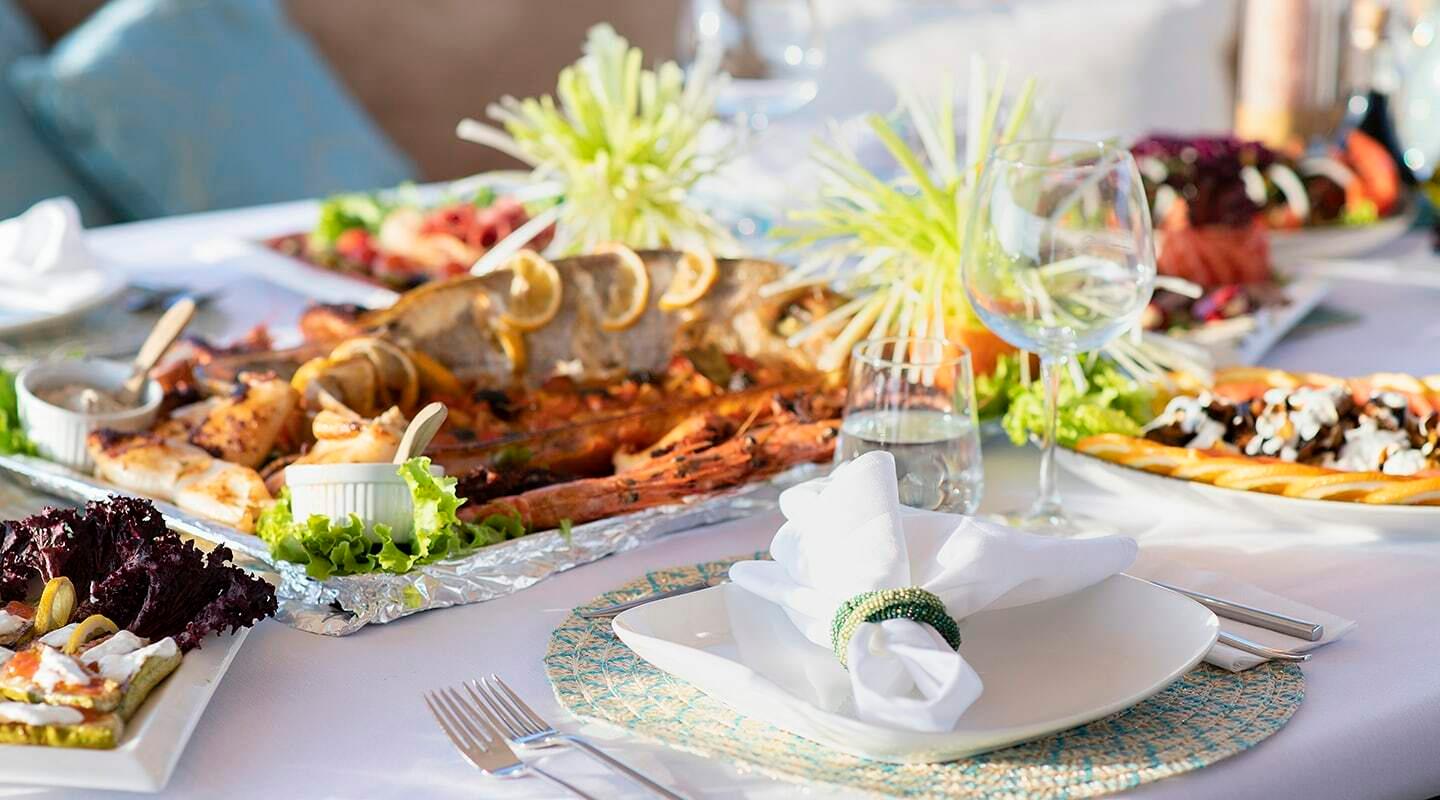 luxury yacht dining table with grilled whole fish, wine glasses, and decorative garnishes