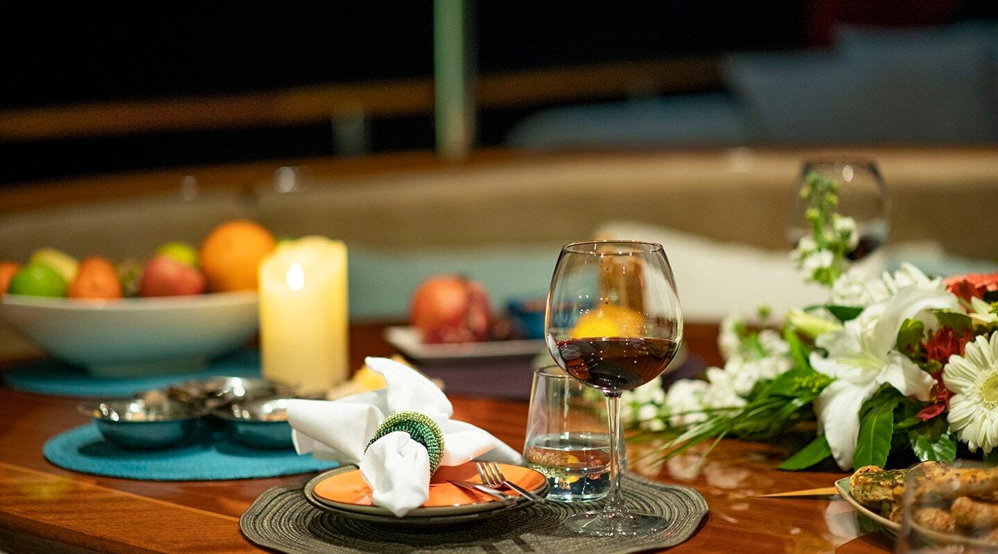 elegant yacht dining table with wine glasses, candle, fresh flowers and place settings