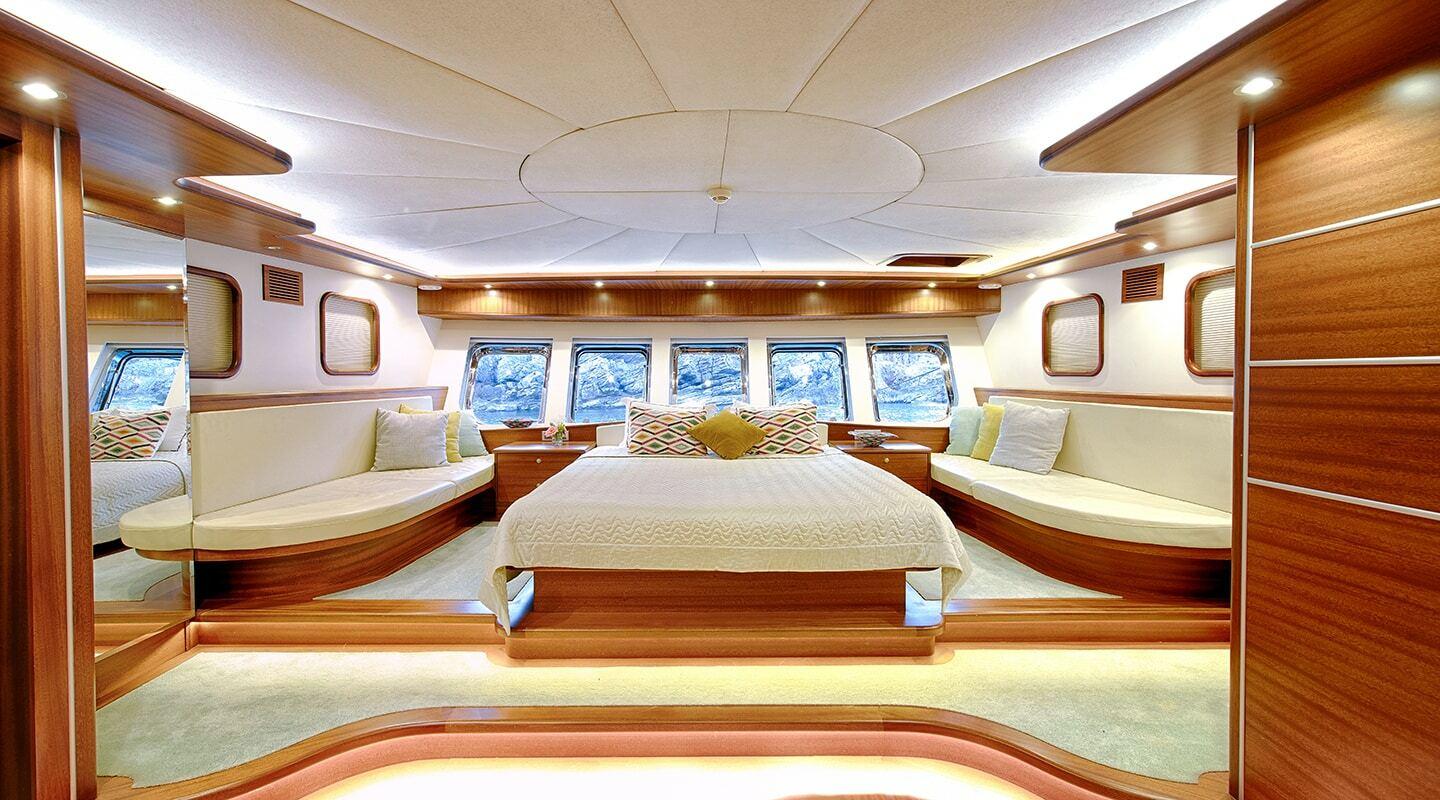 luxury yacht master cabin featuring king bed with cream linens and panoramic side windows