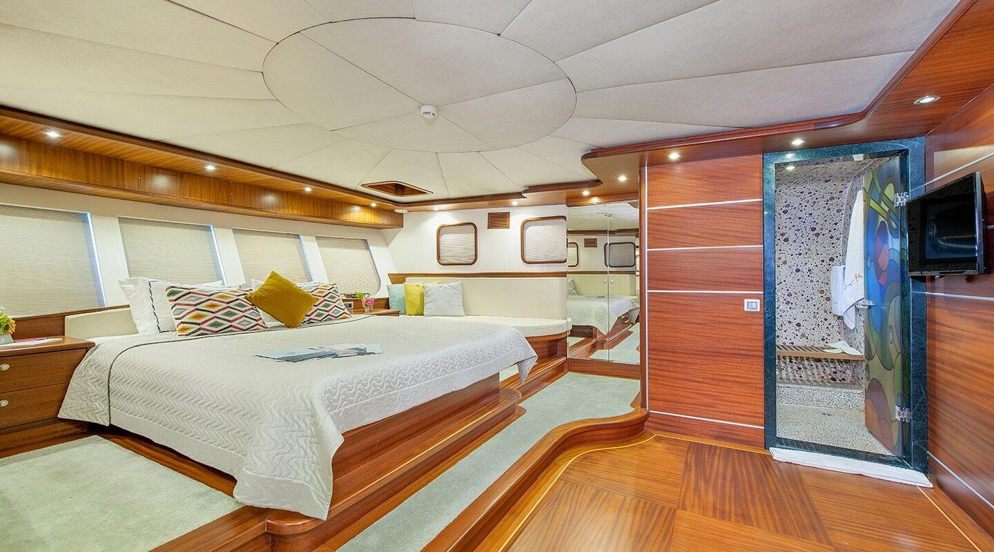 luxury yacht master cabin featuring king bed, wood paneling and en-suite bathroom entrance