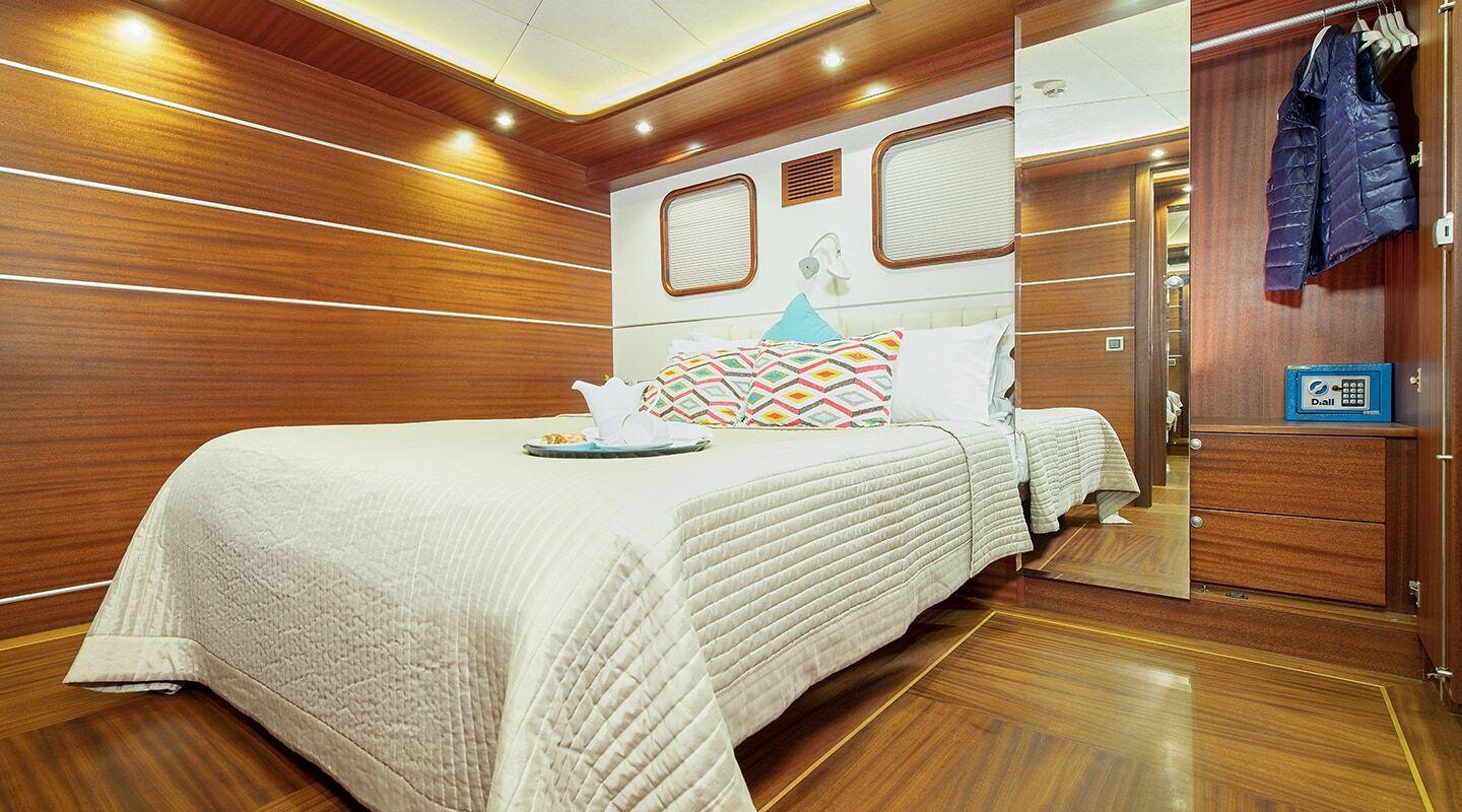 yacht guest cabin featuring double bed with geometric pillows and built-in wardrobe with hanging jacket