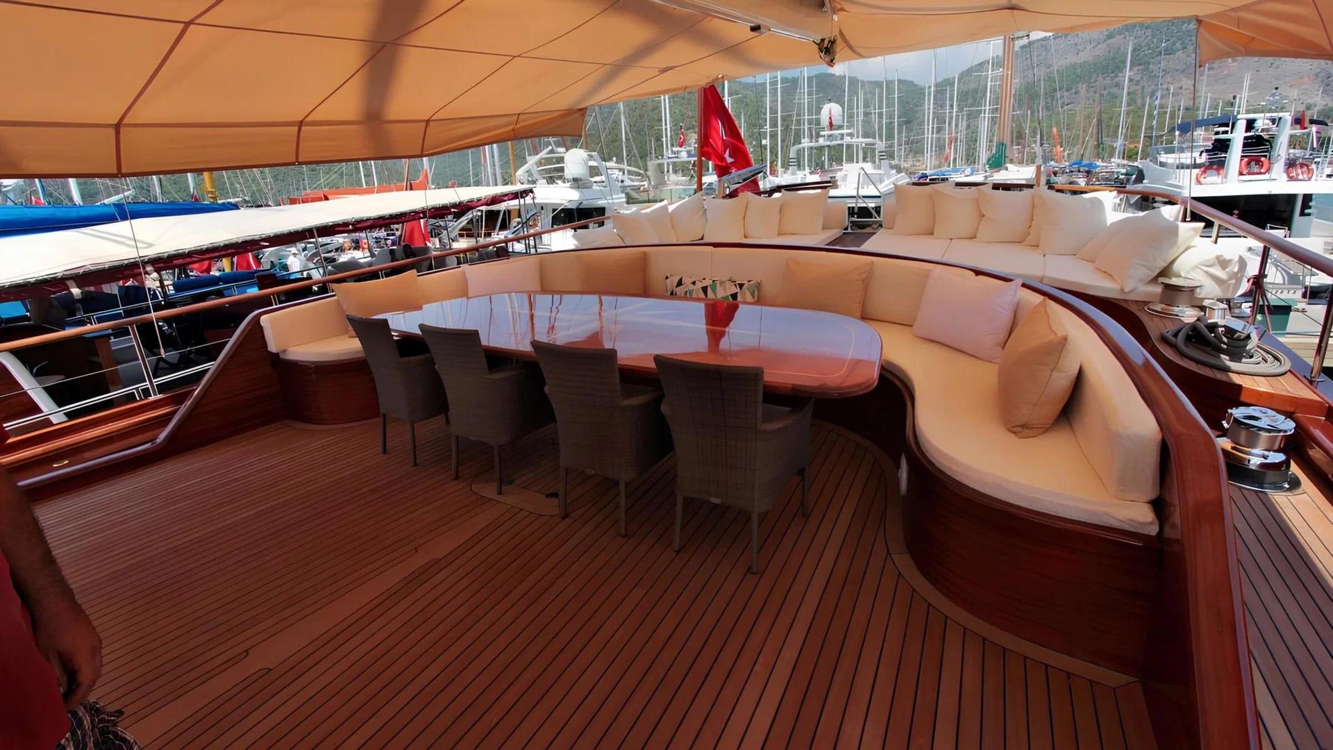 gulet aft deck with curved banquette seating, oval dining table and teak decking