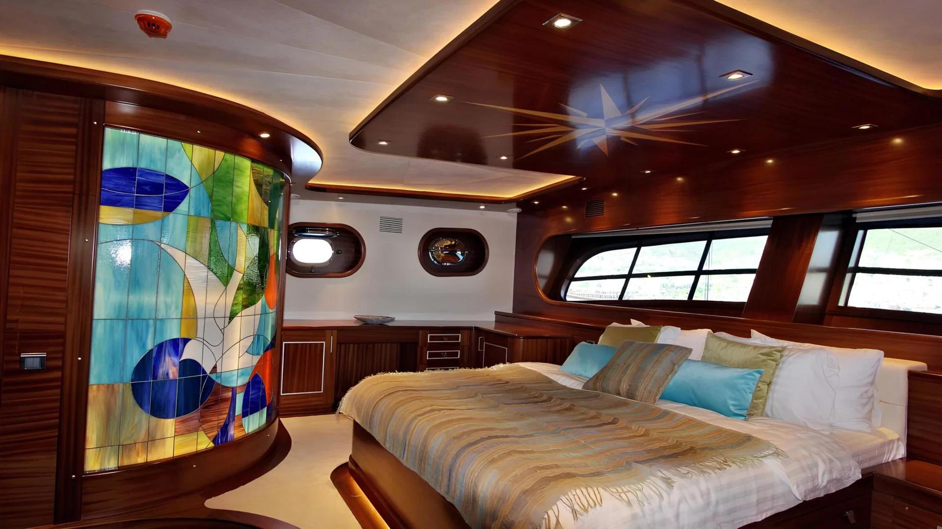 Master cabin with king-size bed, curved stained glass partition, dark wood paneling and panoramic windows