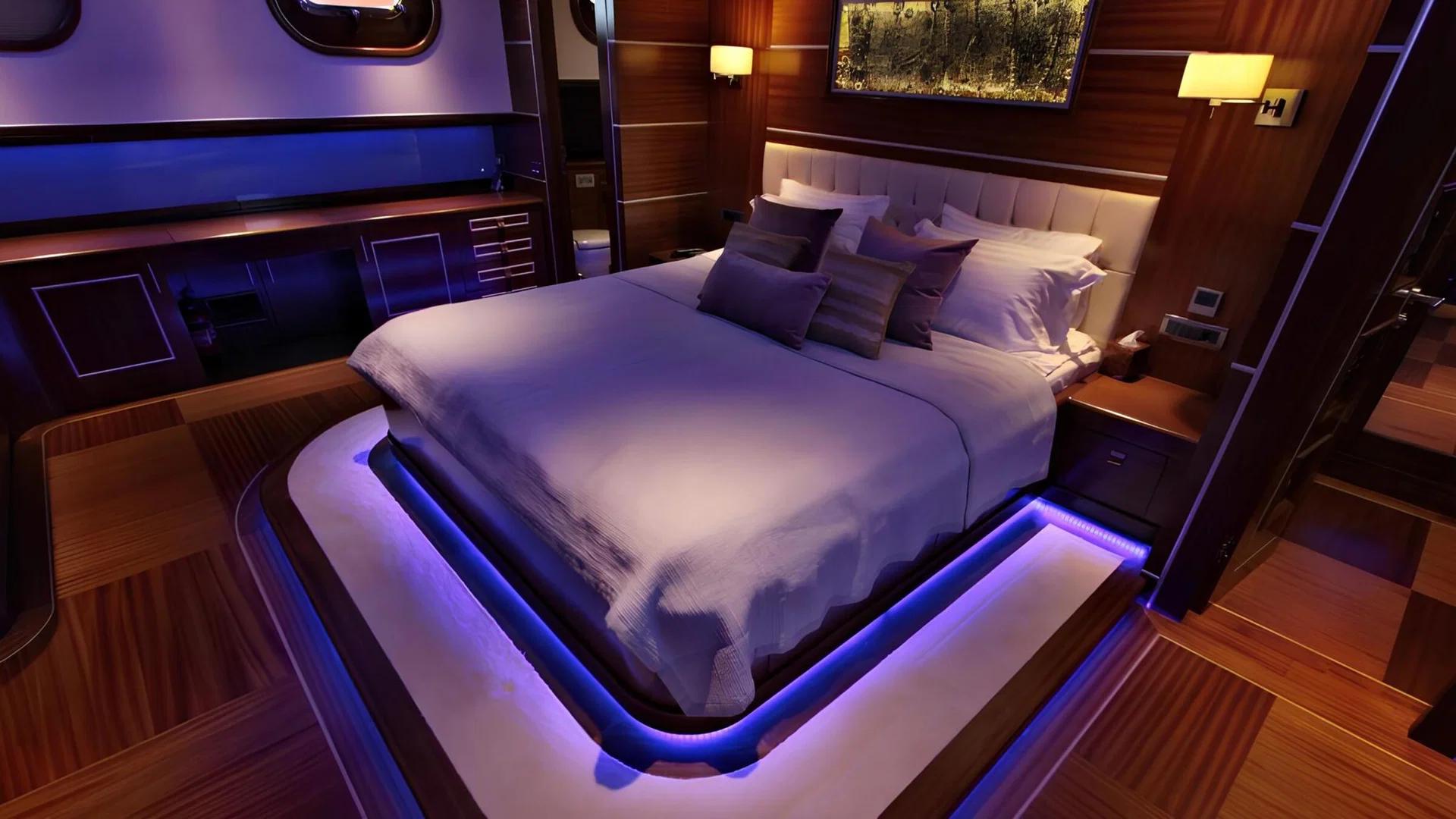 luxury yacht master cabin featuring king bed with white linens and blue LED ambient lighting