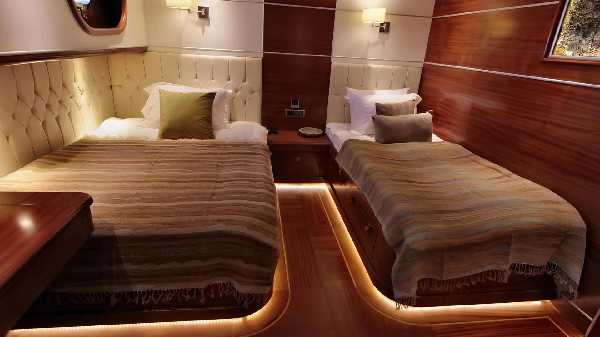 yacht twin cabin featuring two single beds with cream upholstered headboards and LED accent lighting