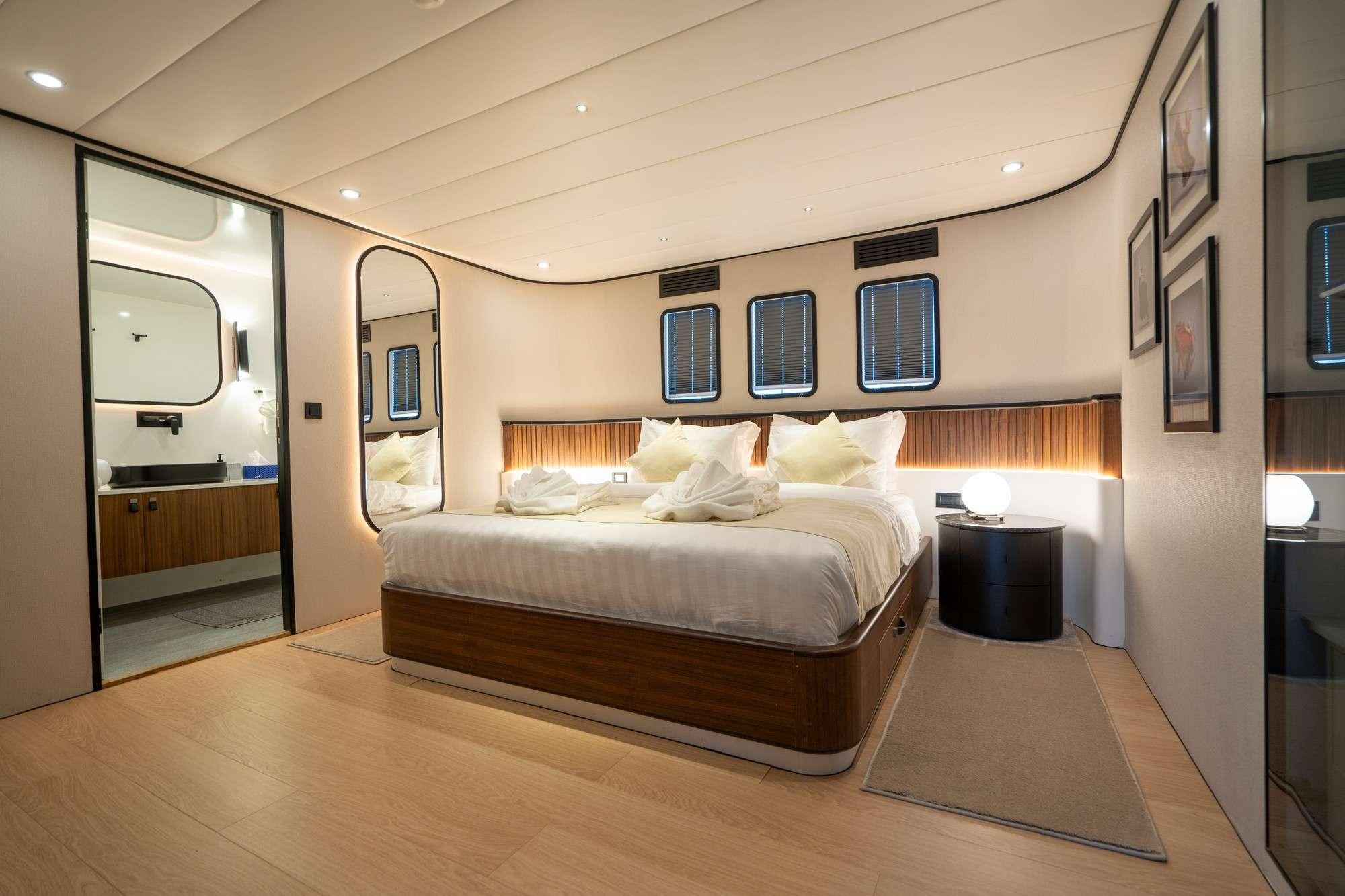 luxury yacht master cabin featuring king bed, wood headboard, ensuite bathroom and hull windows