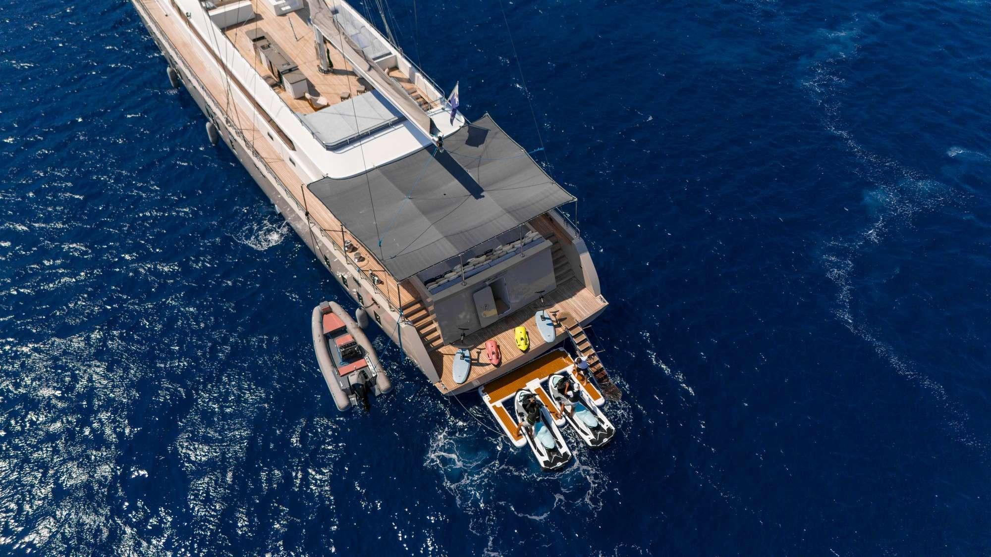 aerial view of luxury yacht stern showing swim platform with jet skis and tender boat