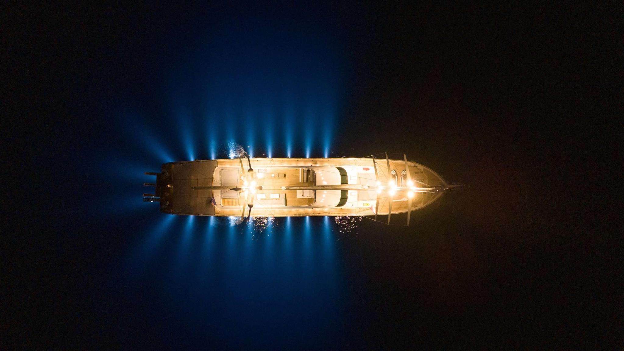 aerial nighttime view of illuminated luxury yacht anchored in dark waters