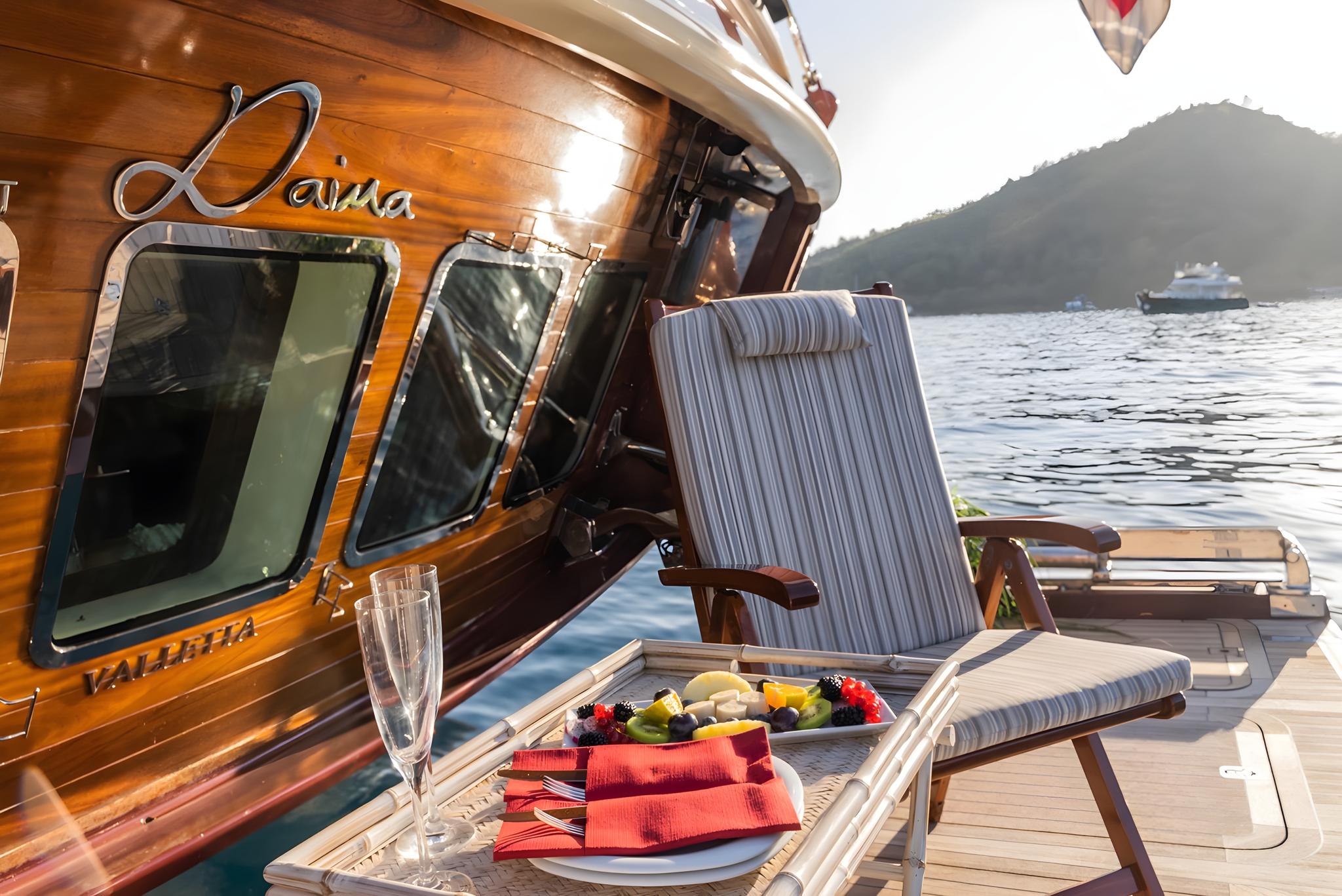Yacht deck dining scene with fresh fruit platter, champagne flute and red napkins